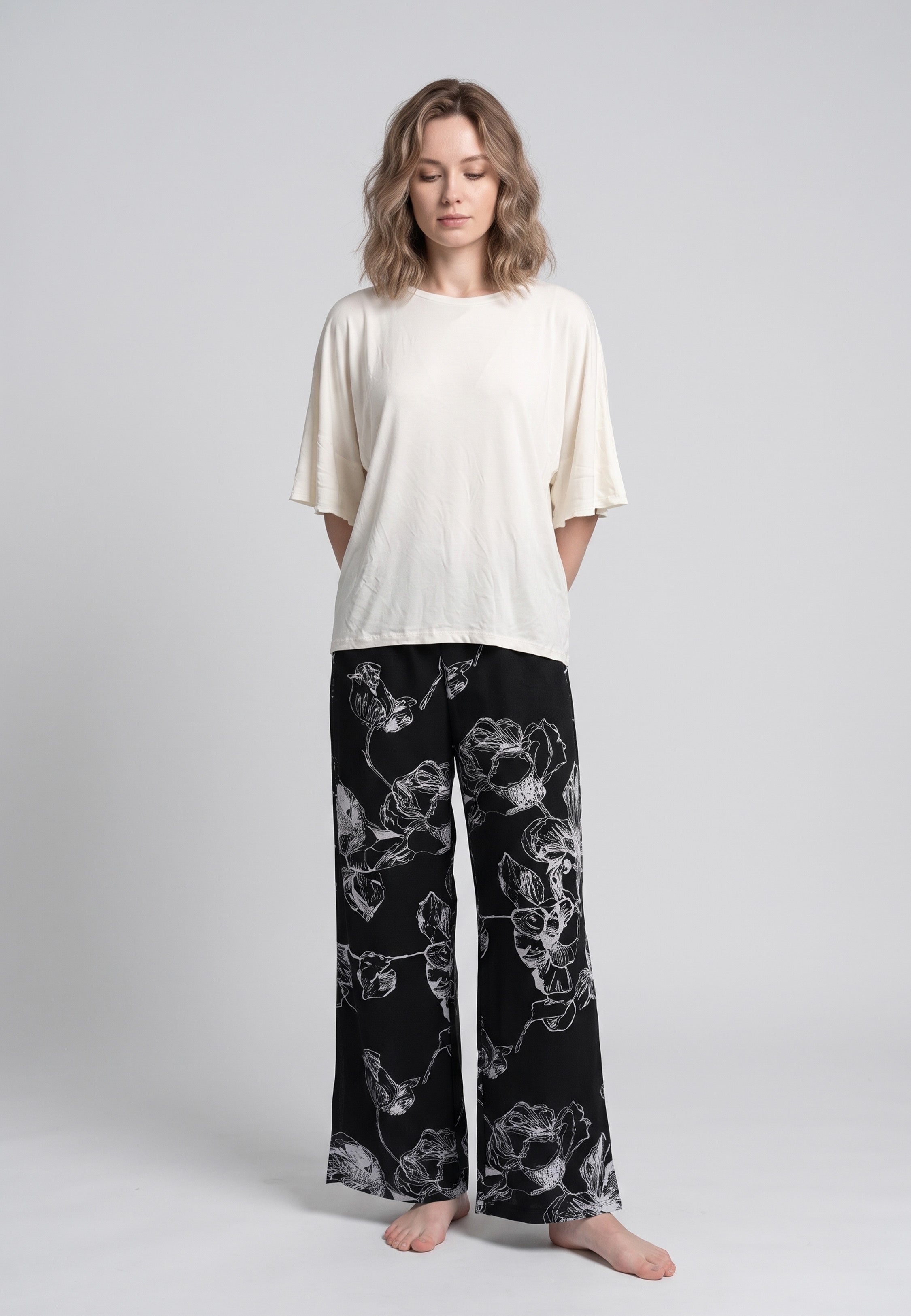 Pyjama pantalon long deux pièces T-shirt col rond écru manches évasées et pantalon large fond noir imprimé grandes fleurs botaniques écru
