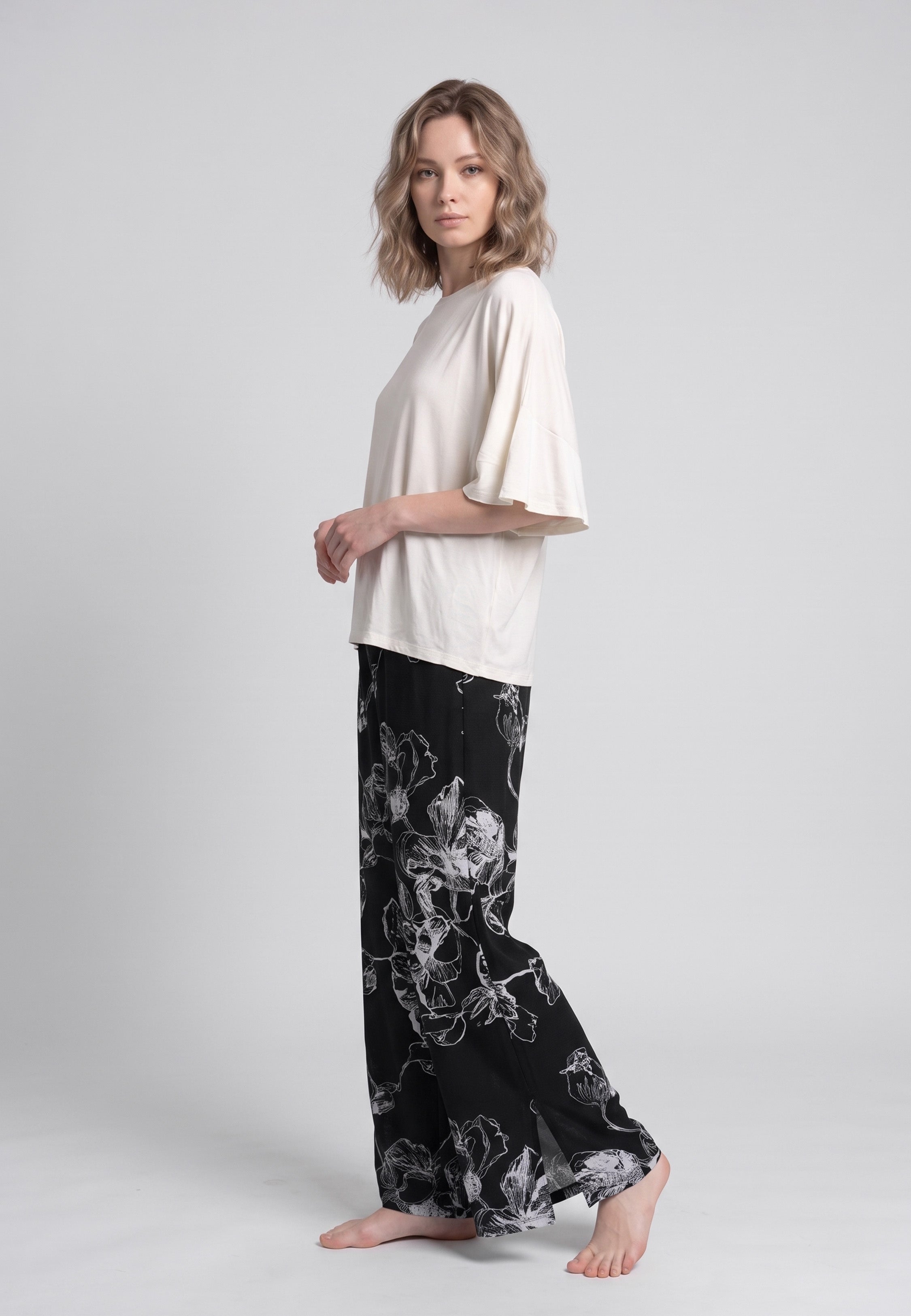 Pyjama pantalon long deux pièces T-shirt col rond écru manches évasées et pantalon large fond noir imprimé grandes fleurs botaniques écru