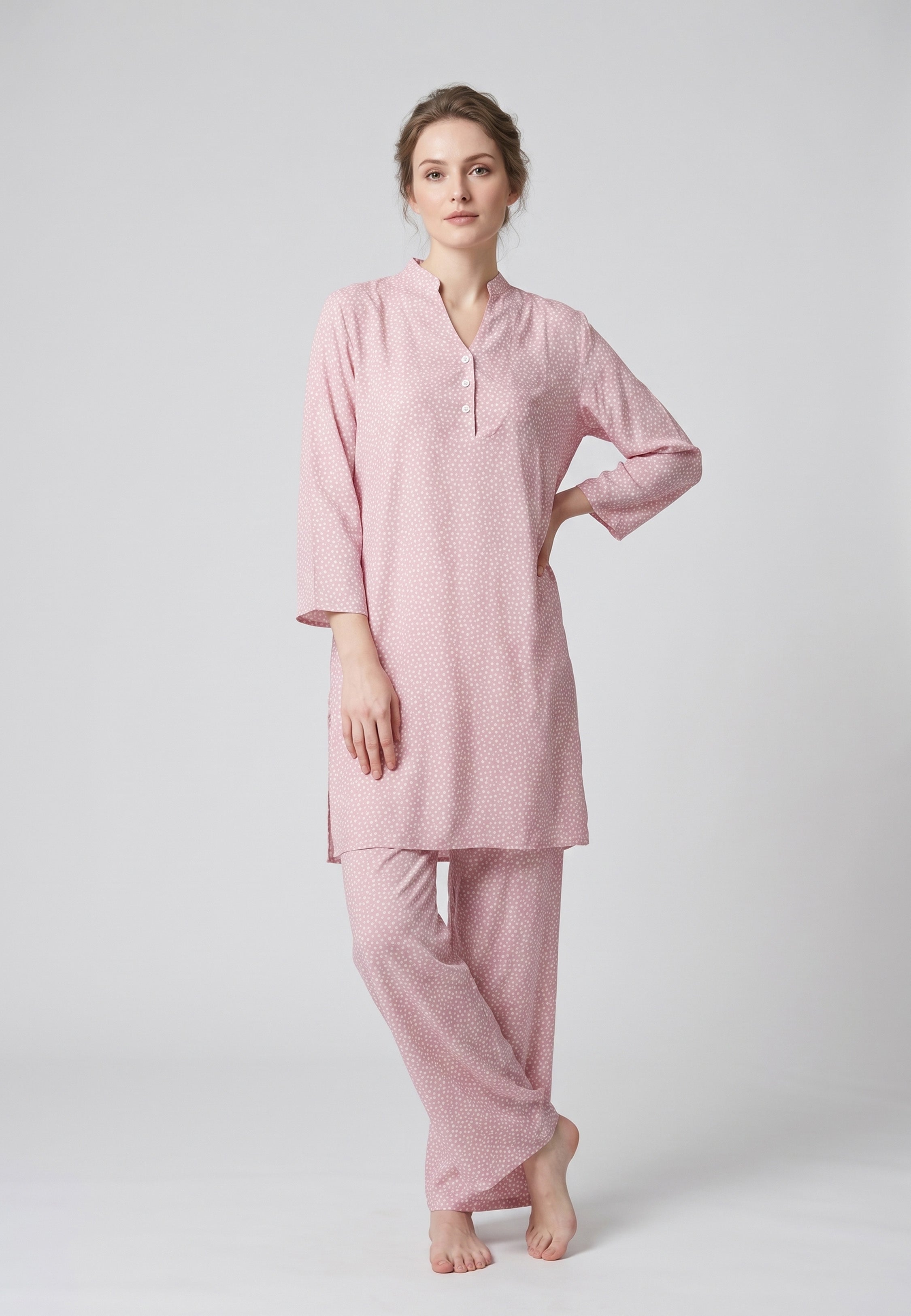Femme portant un pyjama deux pièces rose à imprimé pois blancs
