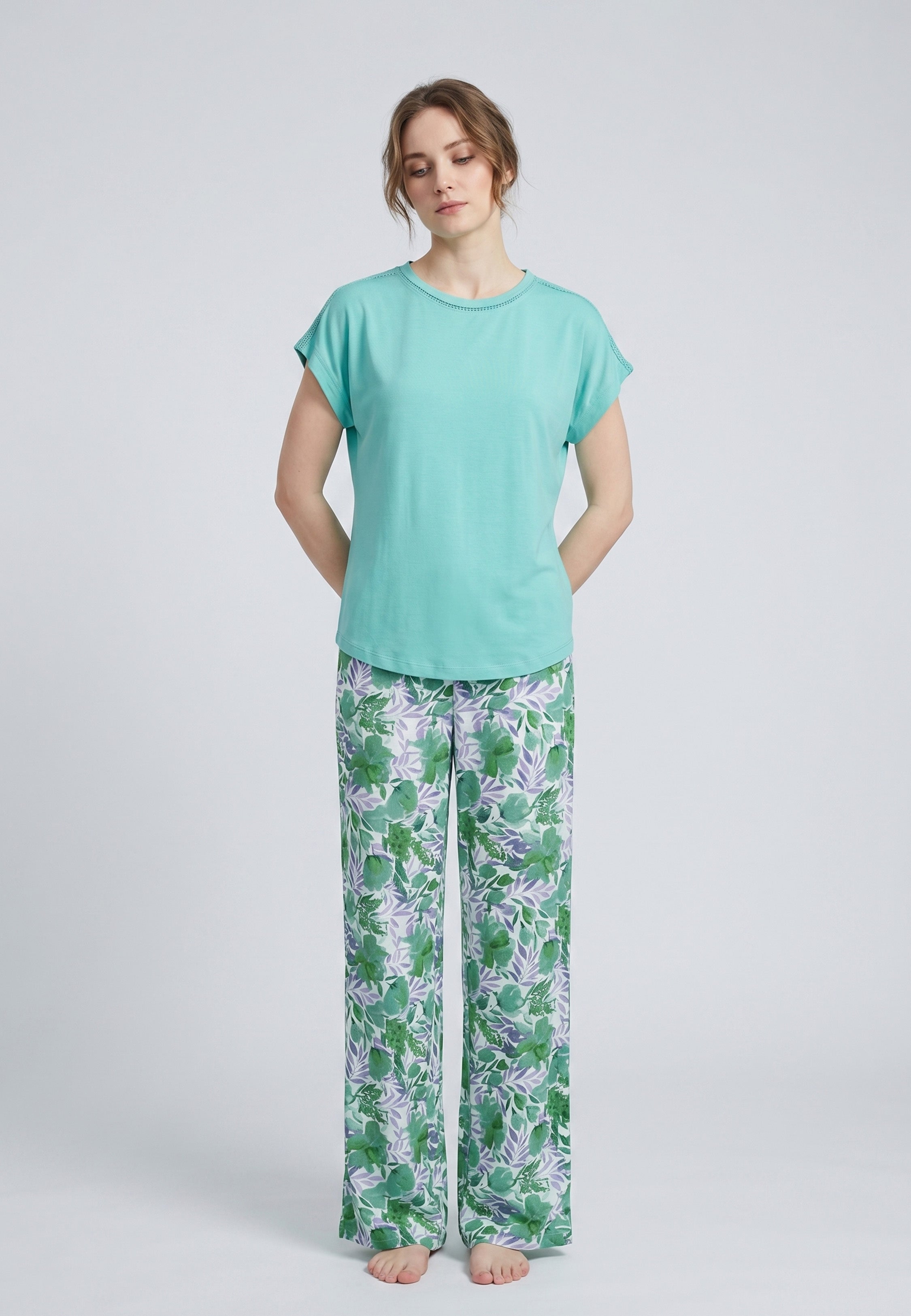 Femme portant un pyjama deux pièces haut uni vert col rond ajouré et pantalon à imprimé floral vert et violet