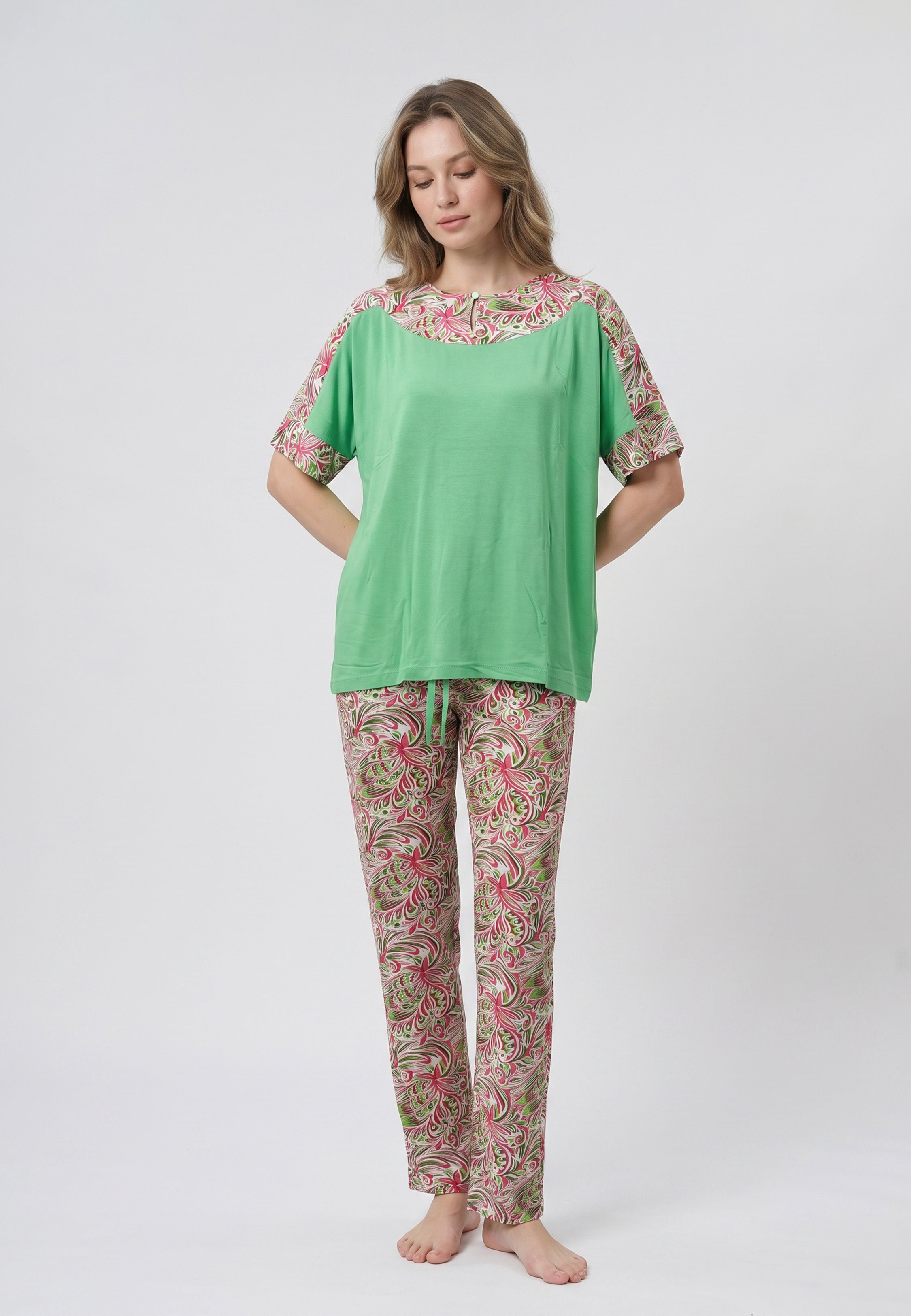 Femme portant un pyjama deux pièces t-shirt vert à empiècement fleuri et pantalon long imprimé ethnique floral multicolore sur fond gris Rosabella Ethnique 2