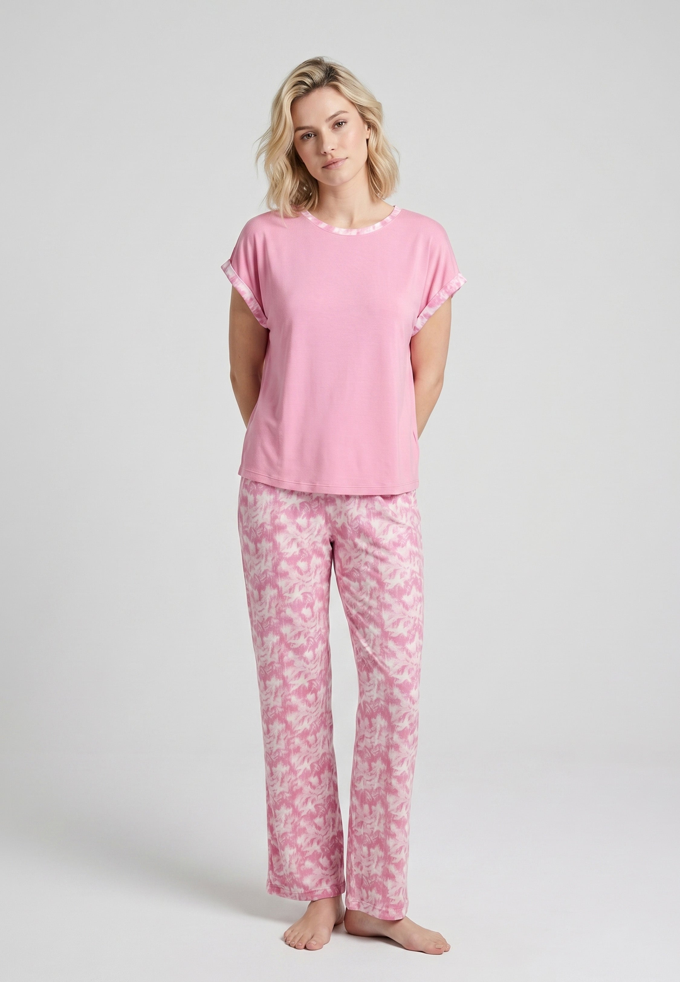 Femme portant un pyjama deux pièces t-shirt rose foncé liseré fleuri au col et manches et pantalon long imprimé aquarelle fleuri multicolore Rosabella Rosalinda
