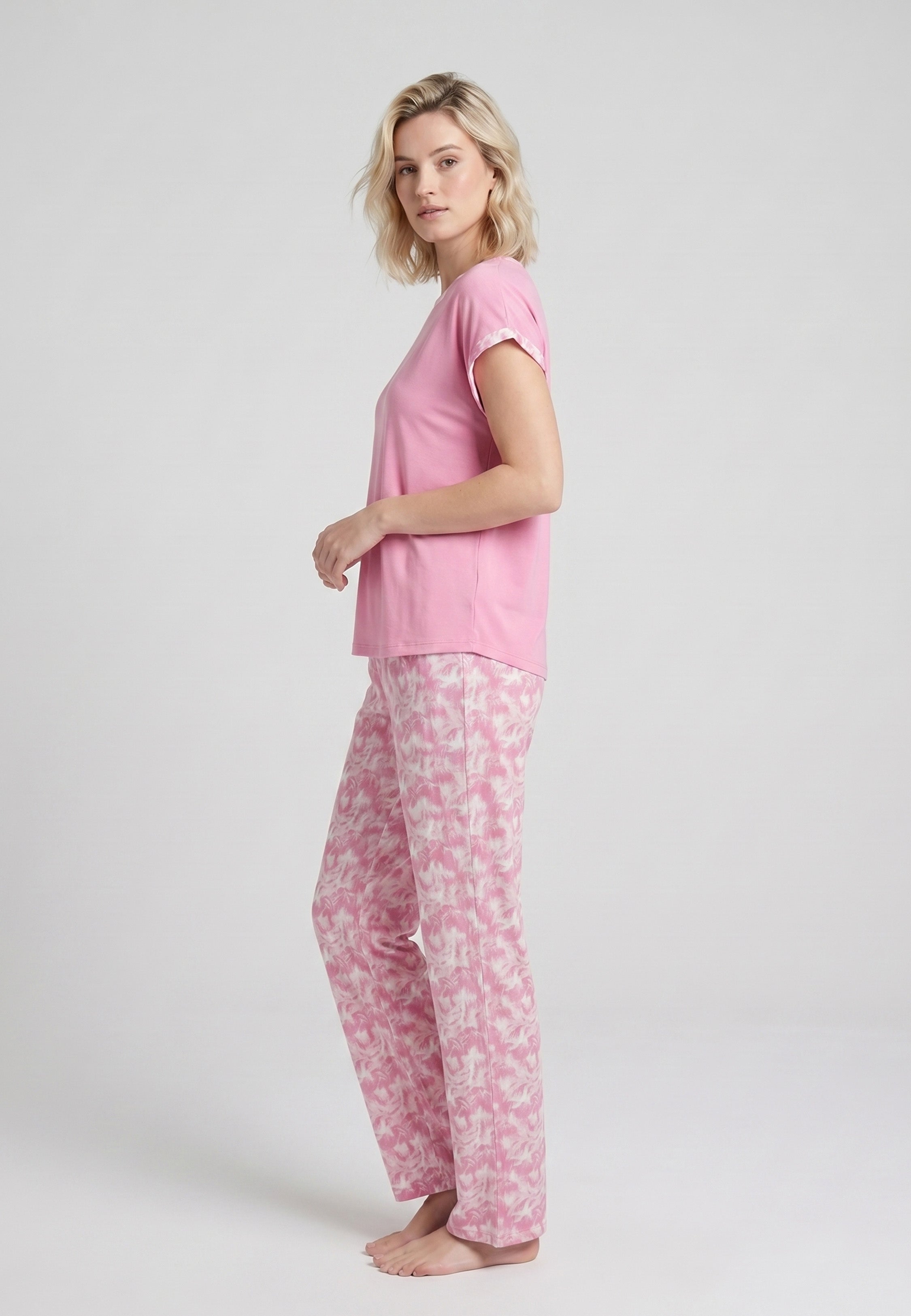 Femme portant un pyjama deux pièces t-shirt rose foncé liseré fleuri au col et manches et pantalon long imprimé aquarelle fleuri multicolore Rosabella Rosalinda