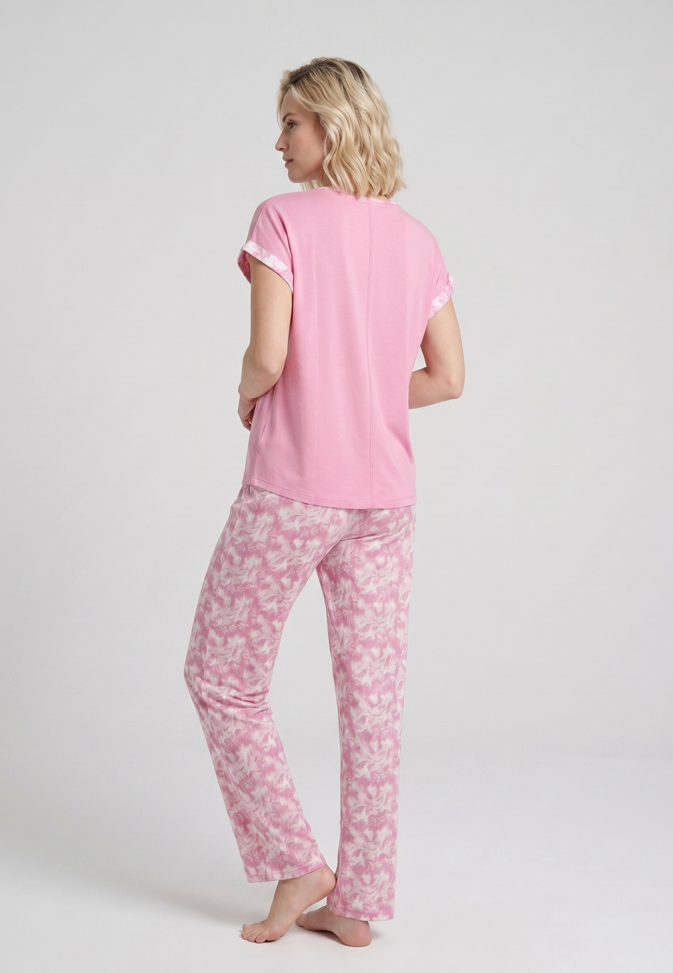 Femme portant un pyjama deux pièces t-shirt rose foncé liseré fleuri au col et manches et pantalon long imprimé aquarelle fleuri multicolore Rosabella Rosalinda