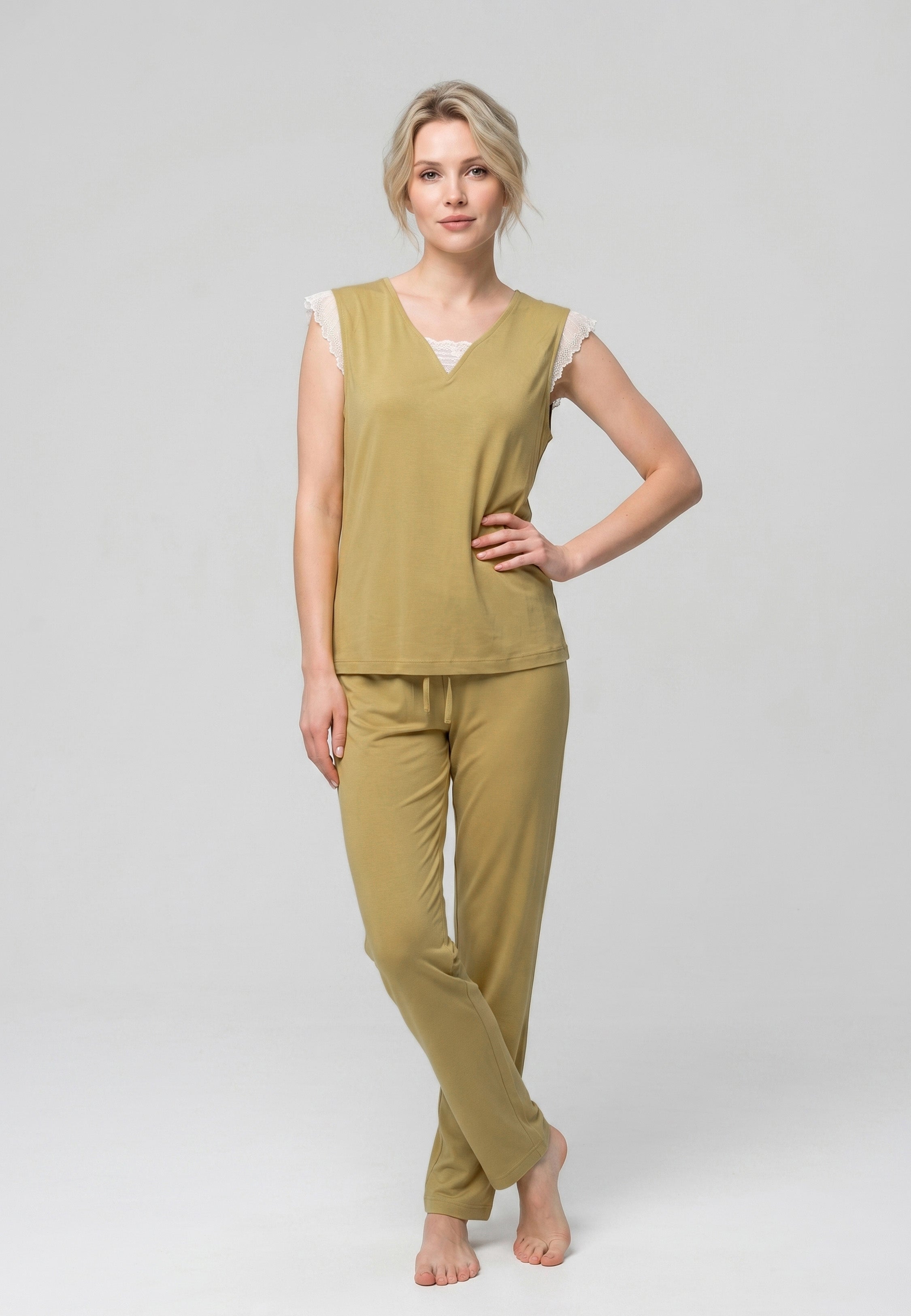Femme portant un pyjama deux pièces uni moutarde avec détails en dentelle crème et pantalon assorti