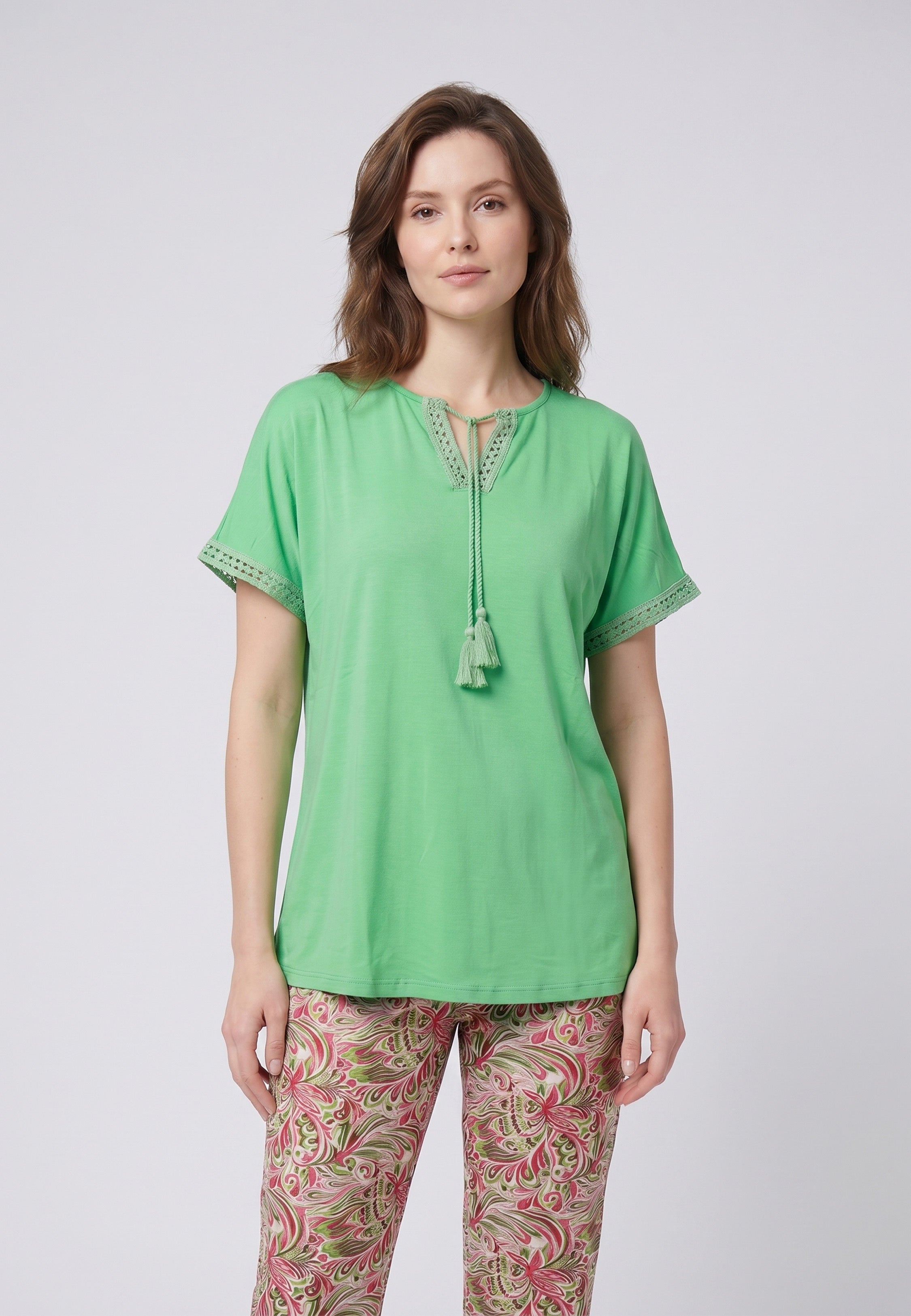 Femme portant un pyjama deux pièces top vert broderie et lacets pompons au col et pantalon long imprimé ethnique floral multicolore Rosabella Ethnique 2
