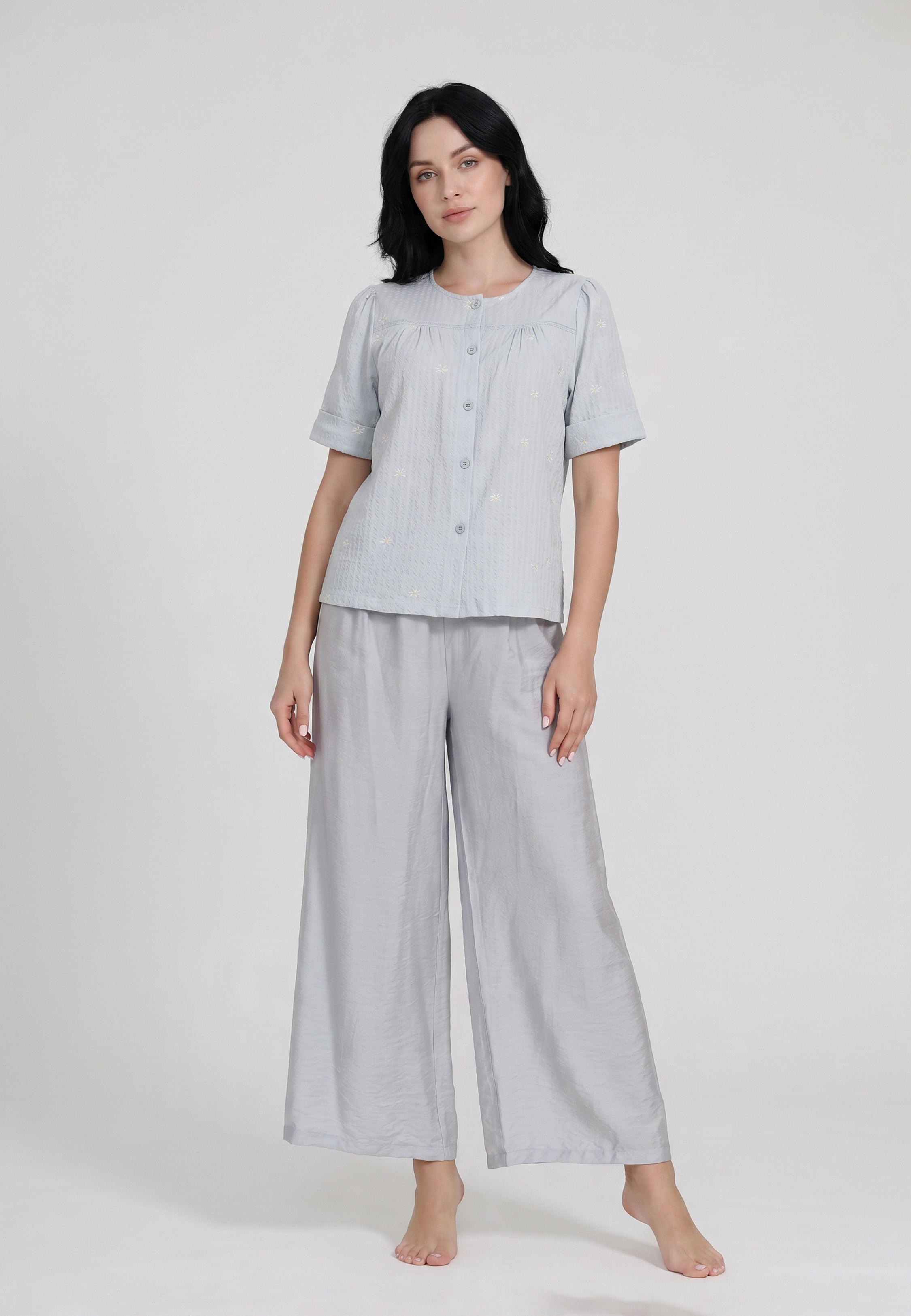 Femme portant un ensemble chemise boutonnée col rond empiècement froncé broderies florales unie bleu ciel manches courtes revers et pantalon palazzo fluide taille élastique ton sur ton Rosabella