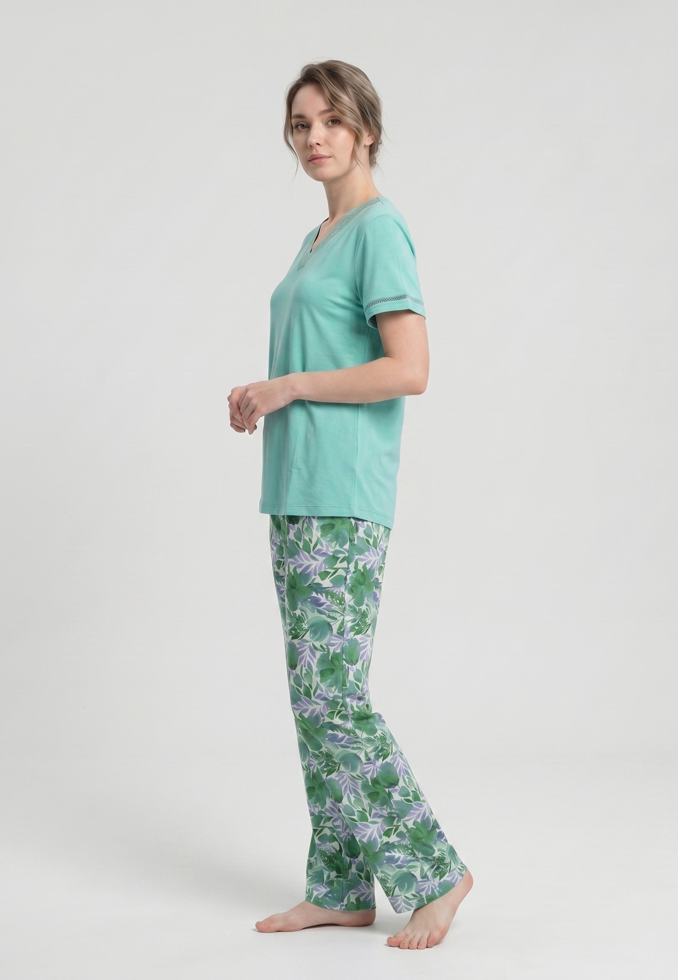 Femme portant un pyjama deux pièces t-shirt vert clair col V broderie anglaise et pantalon long imprimé feuillage botanique vert et lavande Rosabella Fleurs Sauvages