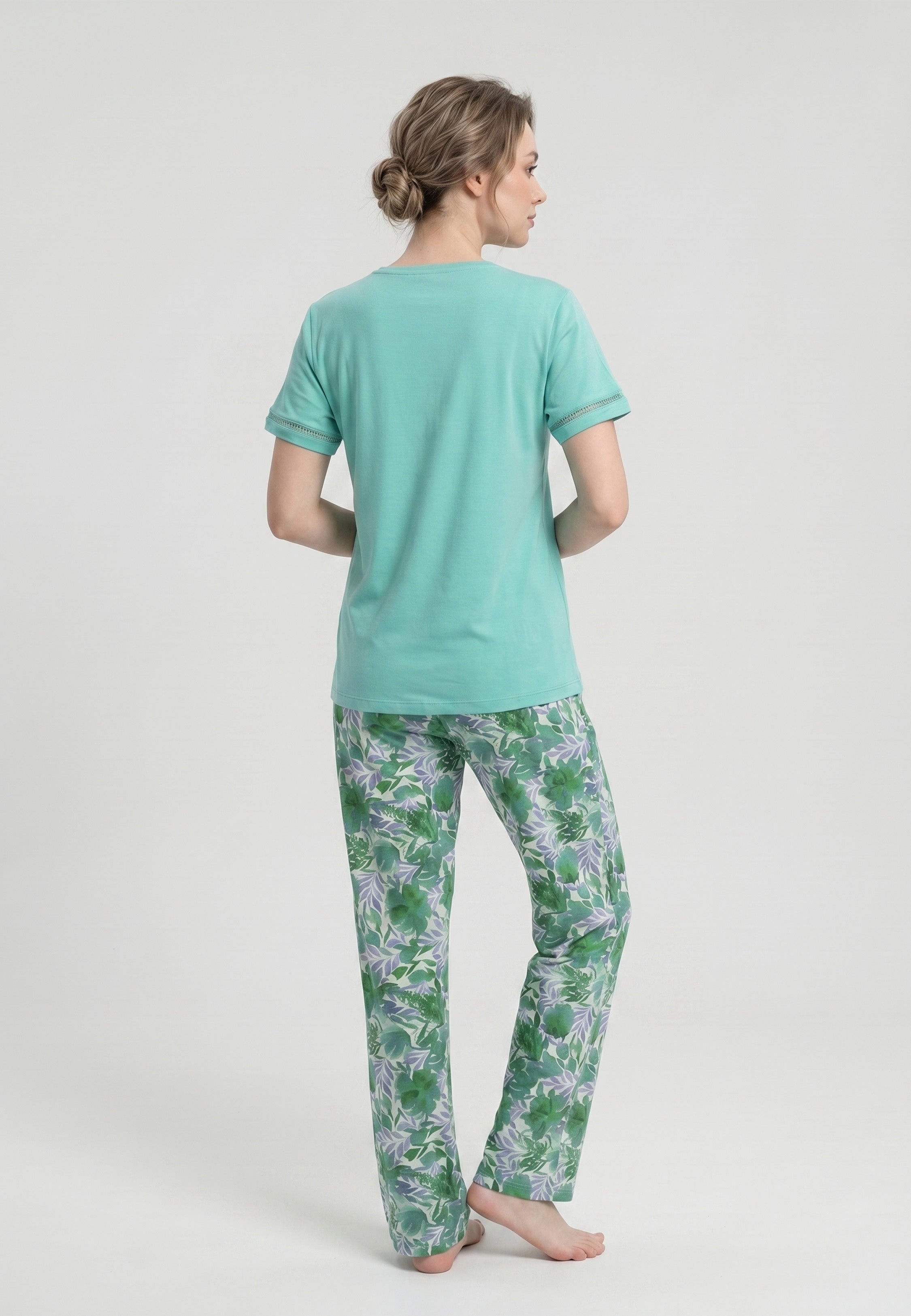 Femme portant un pyjama deux pièces t-shirt vert clair col V broderie anglaise et pantalon long imprimé feuillage botanique vert et lavande Rosabella Fleurs Sauvages