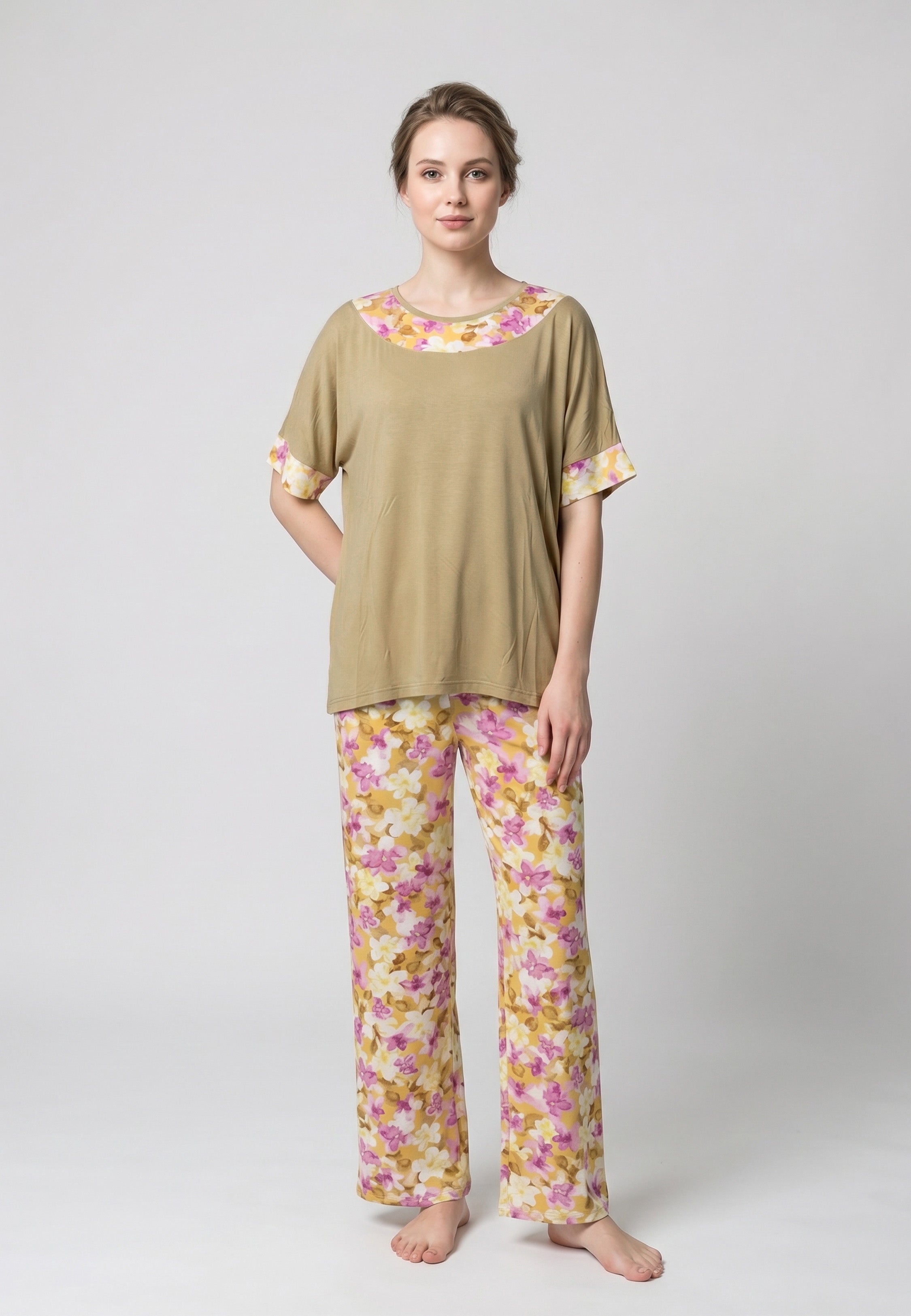Femme portant un pyjama deux pièces haut moutarde oversize avec finition florale rose et jaune et pantalon assorti