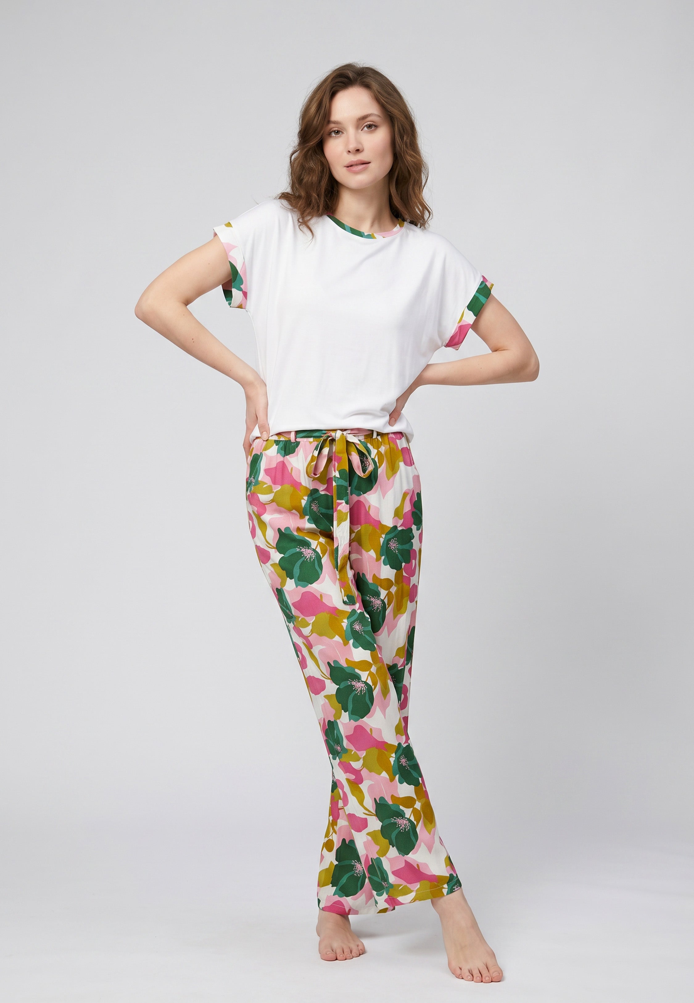 Femme portant un pyjama deux pièces t-shirt blanc liseré fleuri au col et manches et pantalon long grand imprimé fleuri multicolore Rosabella Rosalinda 2
