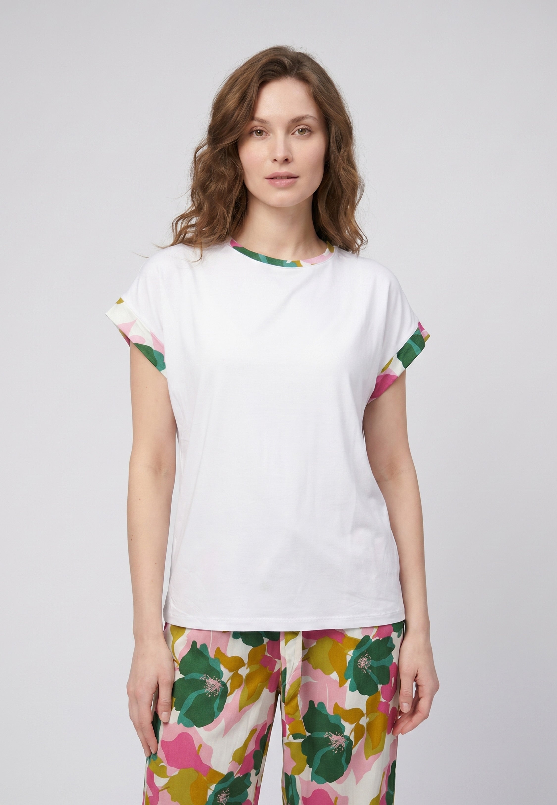 Femme portant un pyjama deux pièces t-shirt blanc liseré fleuri au col et manches et pantalon long grand imprimé fleuri multicolore Rosabella Rosalinda 2
