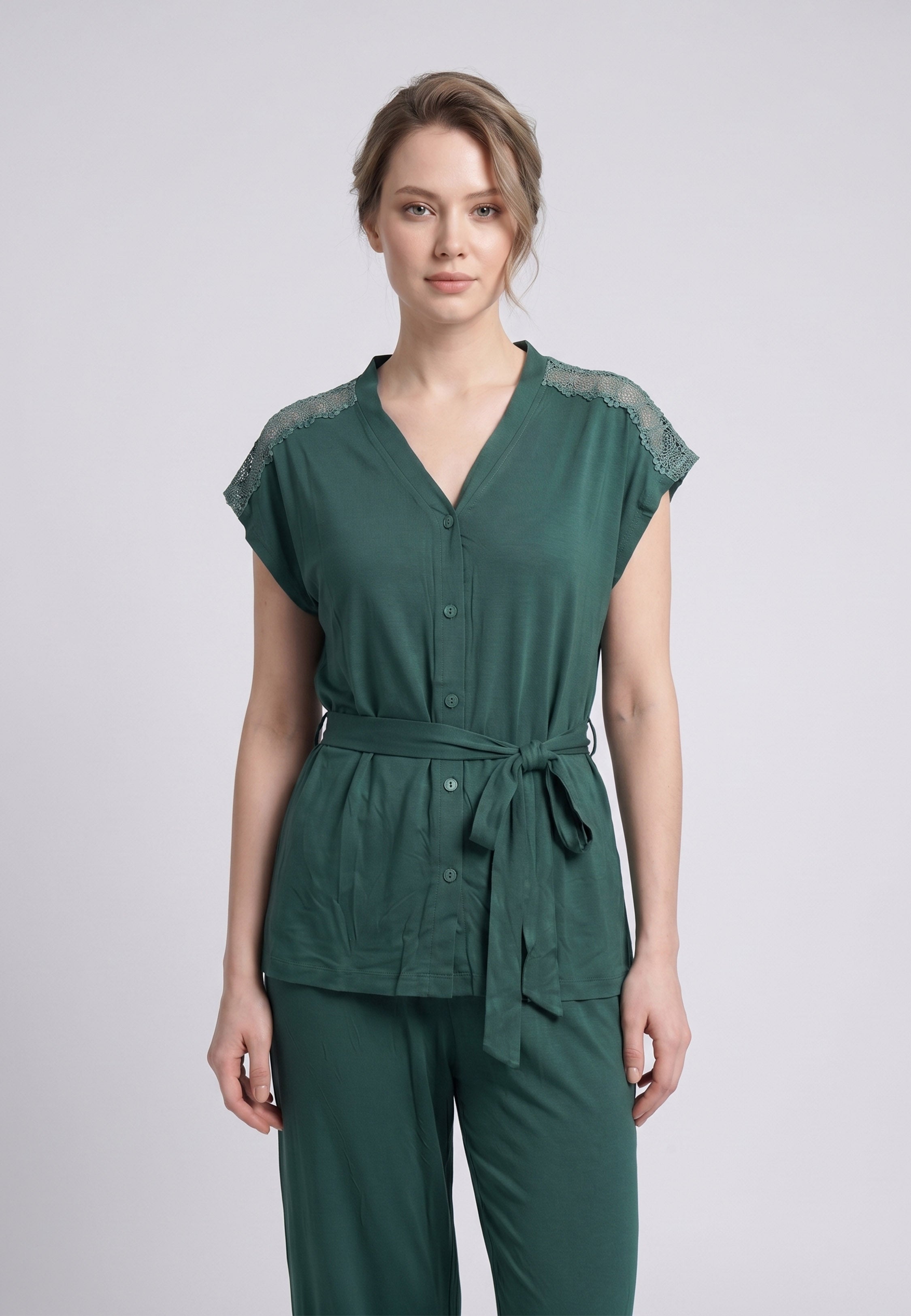 Femme portant un pyjama deux pièces top col V boutonnée broderie épaules ceinture lacet uni vert et pantalon long uni Rosabella Cozy Comforts