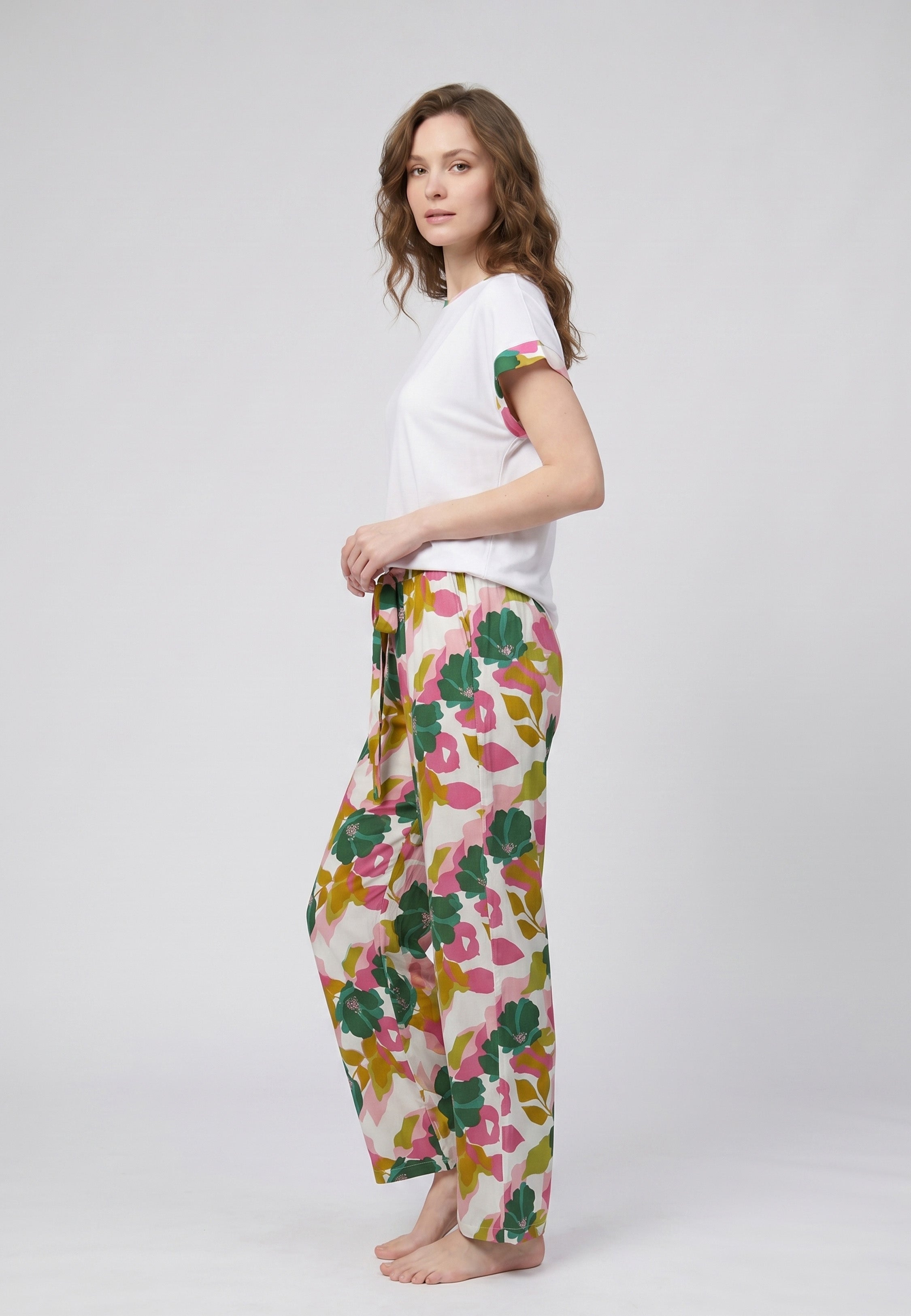 Femme portant un pyjama deux pièces t-shirt blanc liseré fleuri au col et manches et pantalon long grand imprimé fleuri multicolore Rosabella Rosalinda 2