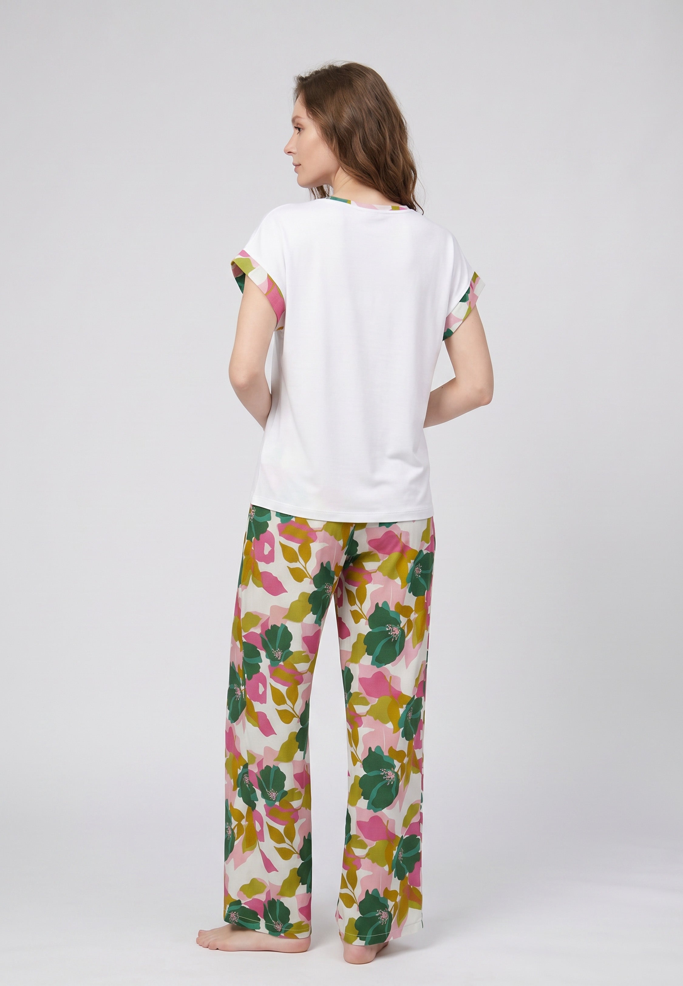 Femme portant un pyjama deux pièces t-shirt blanc liseré fleuri au col et manches et pantalon long grand imprimé fleuri multicolore Rosabella Rosalinda 2