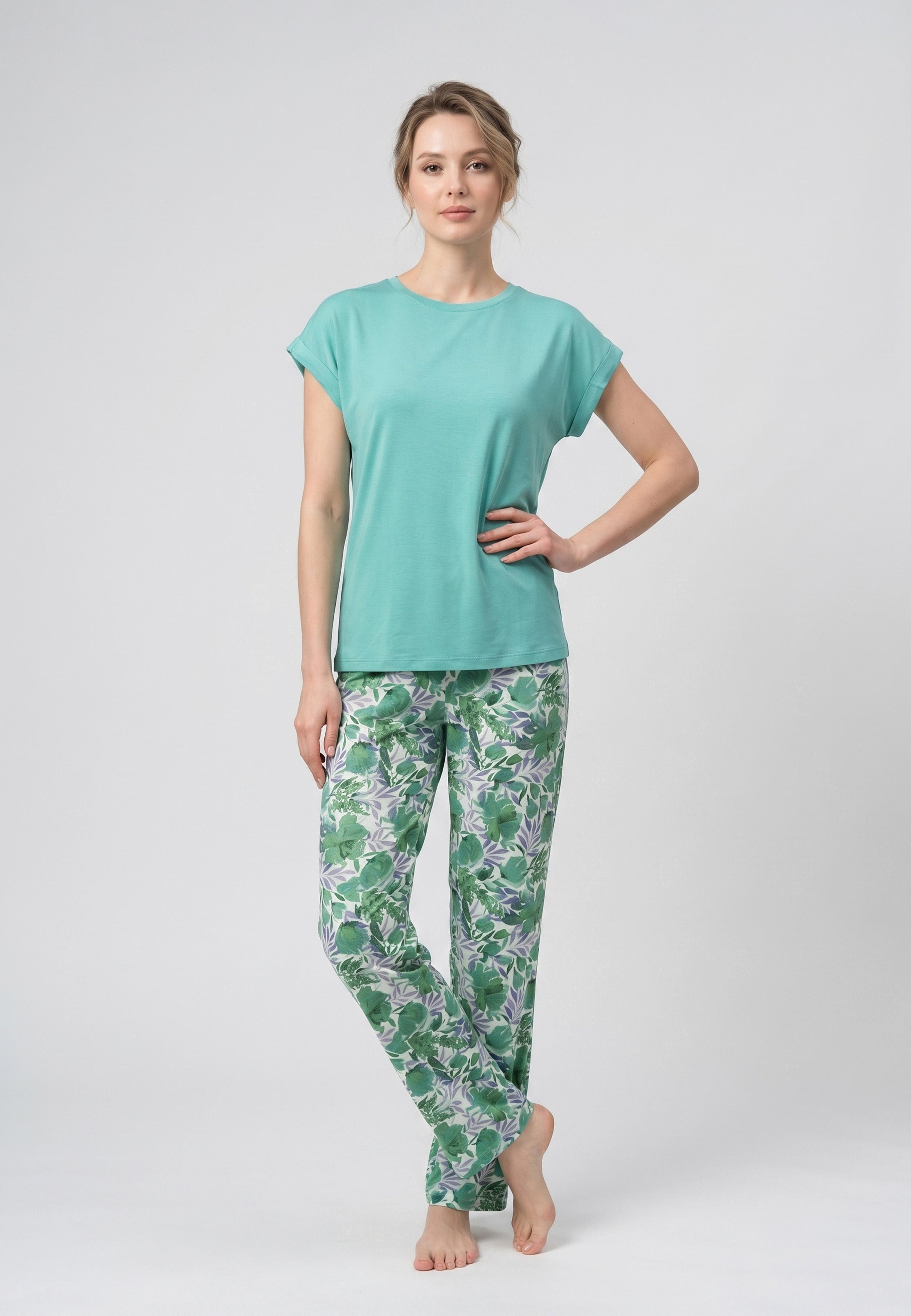 Femme portant un pyjama deux pièces haut uni vert clair et pantalon à imprimé feuilles tropicales vertes et violettes