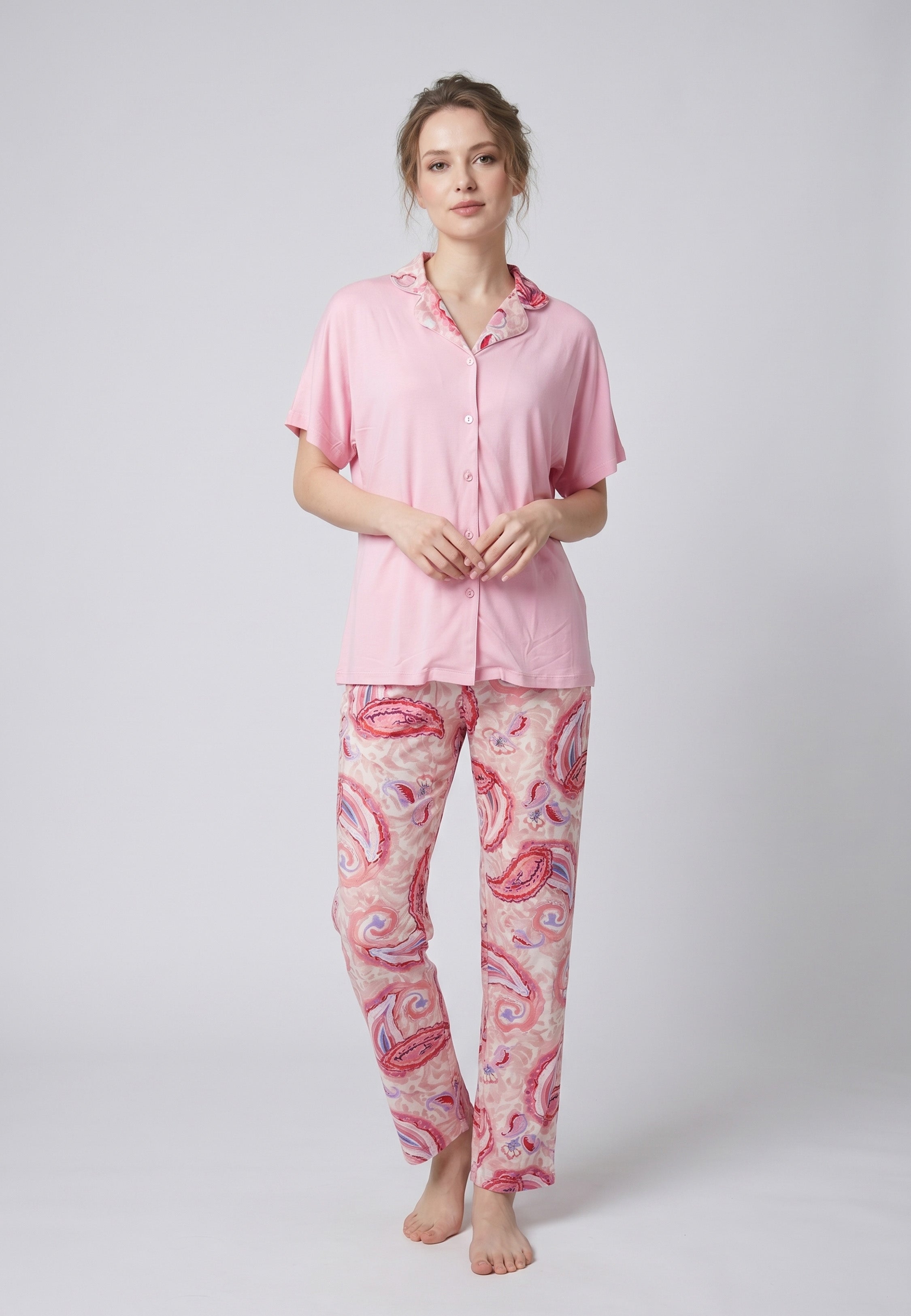 Femme portant un pyjama deux pièces chemise boutonnée manches courtes unie rose liseré imprimé paisley et pantalon droit imprimé paisley multicolore rose et rouge Rosabella Ethnique 2