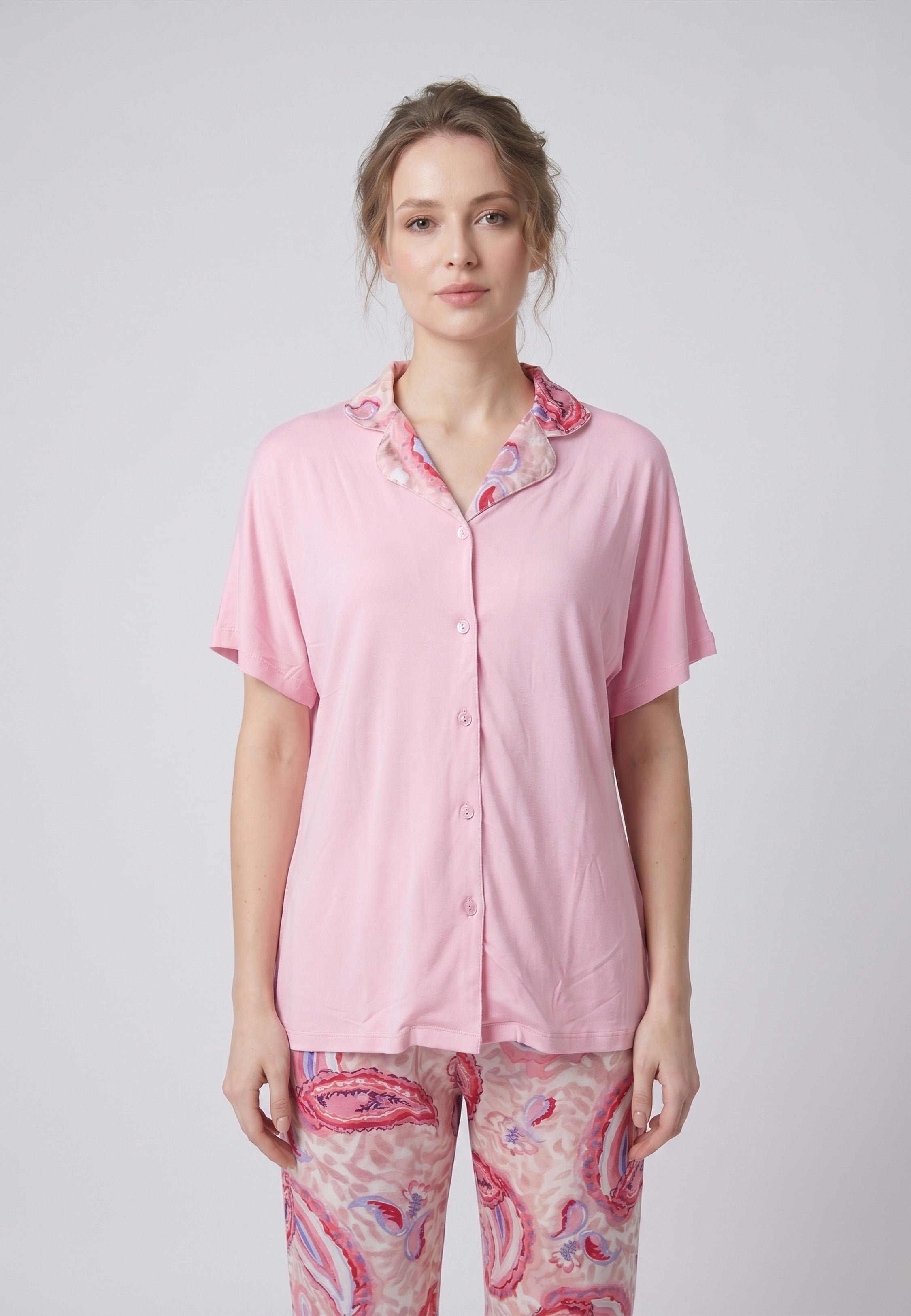 Femme portant un pyjama deux pièces chemise boutonnée manches courtes unie rose liseré imprimé paisley et pantalon droit imprimé paisley multicolore rose et rouge Rosabella Ethnique 2