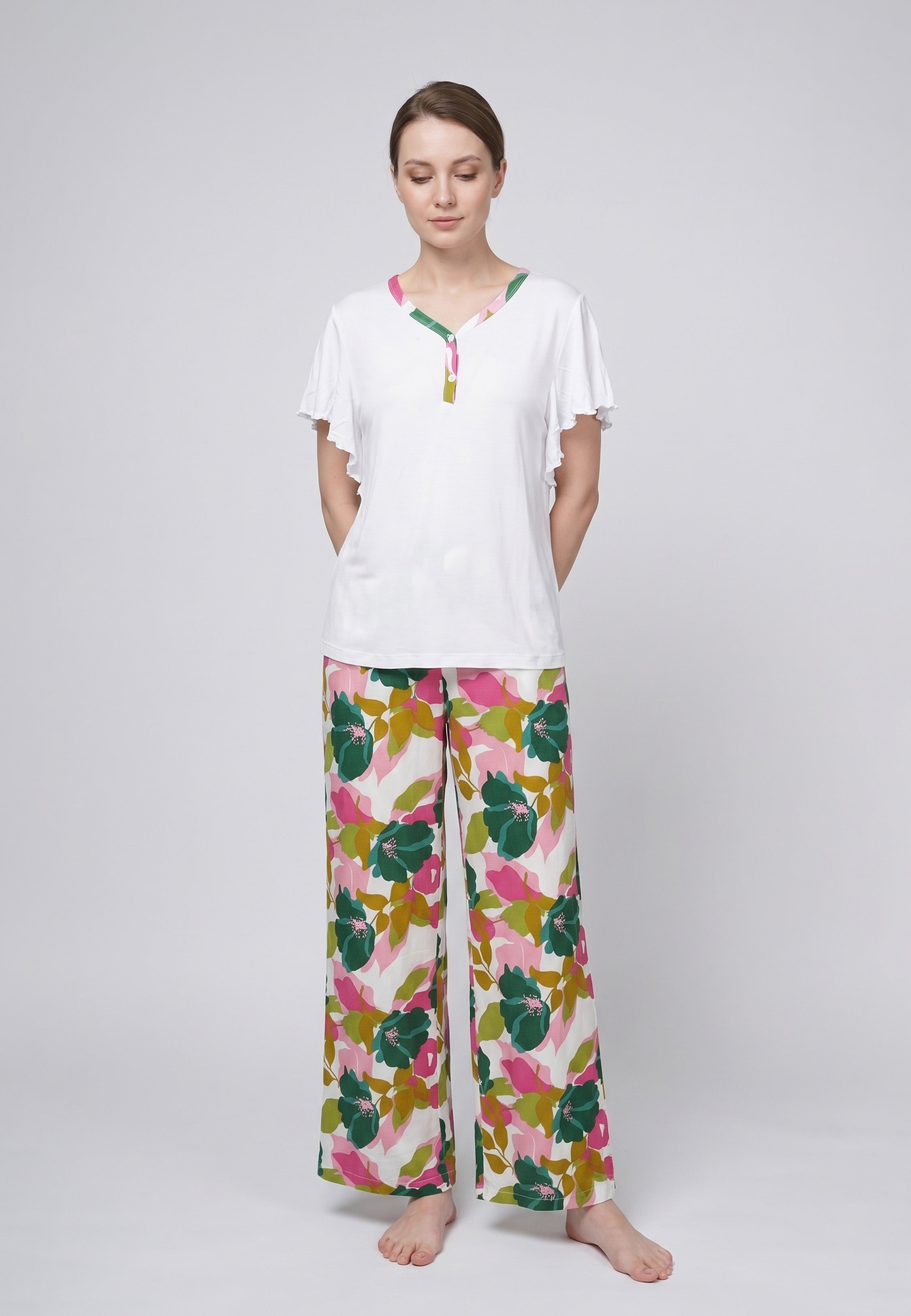 Femme portant un pyjama deux pièces haut blanc manches papillon et pantalon à imprimé floral vert et rose