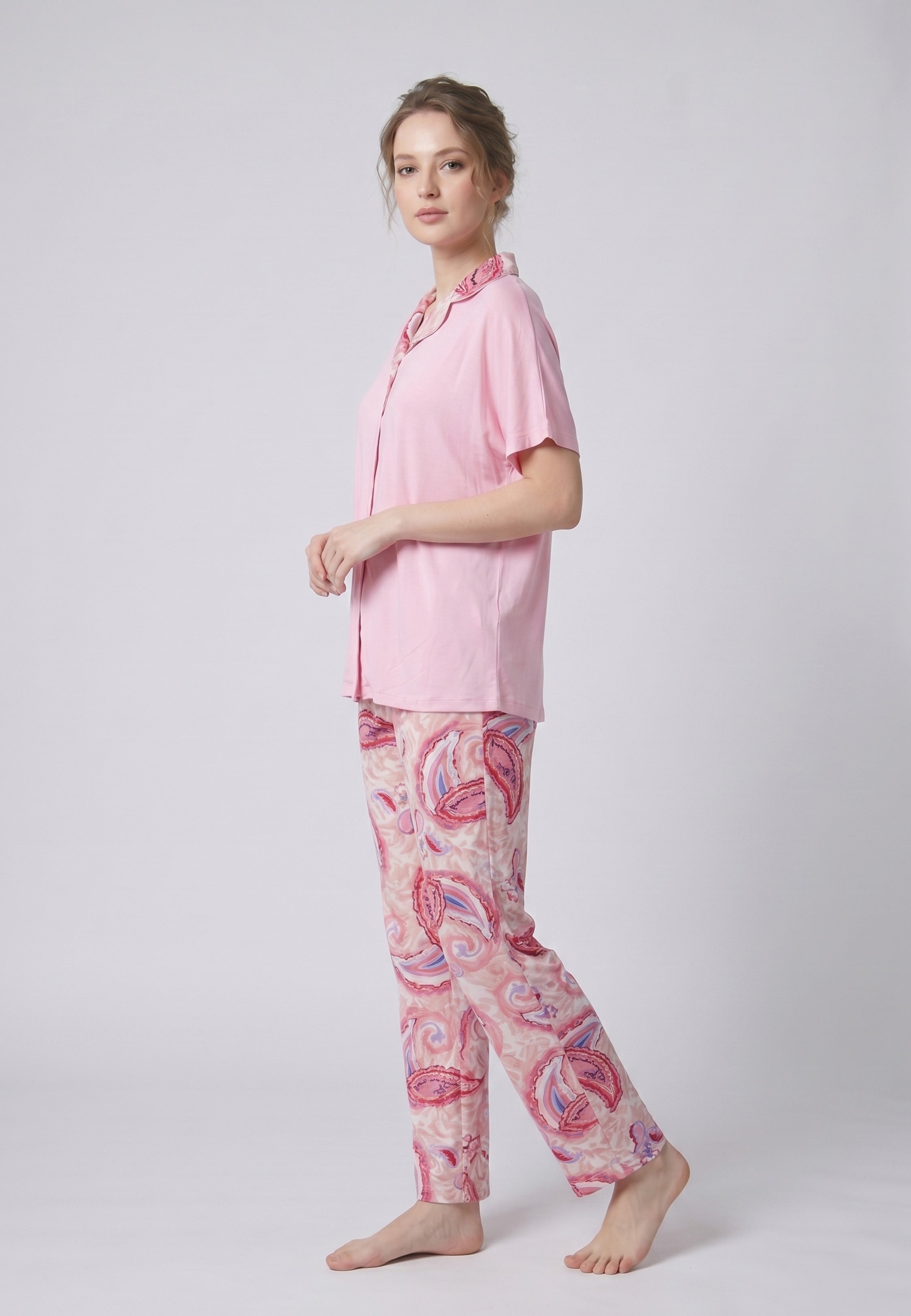 Femme portant un pyjama deux pièces chemise boutonnée manches courtes unie rose liseré imprimé paisley et pantalon droit imprimé paisley multicolore rose et rouge Rosabella Ethnique 2