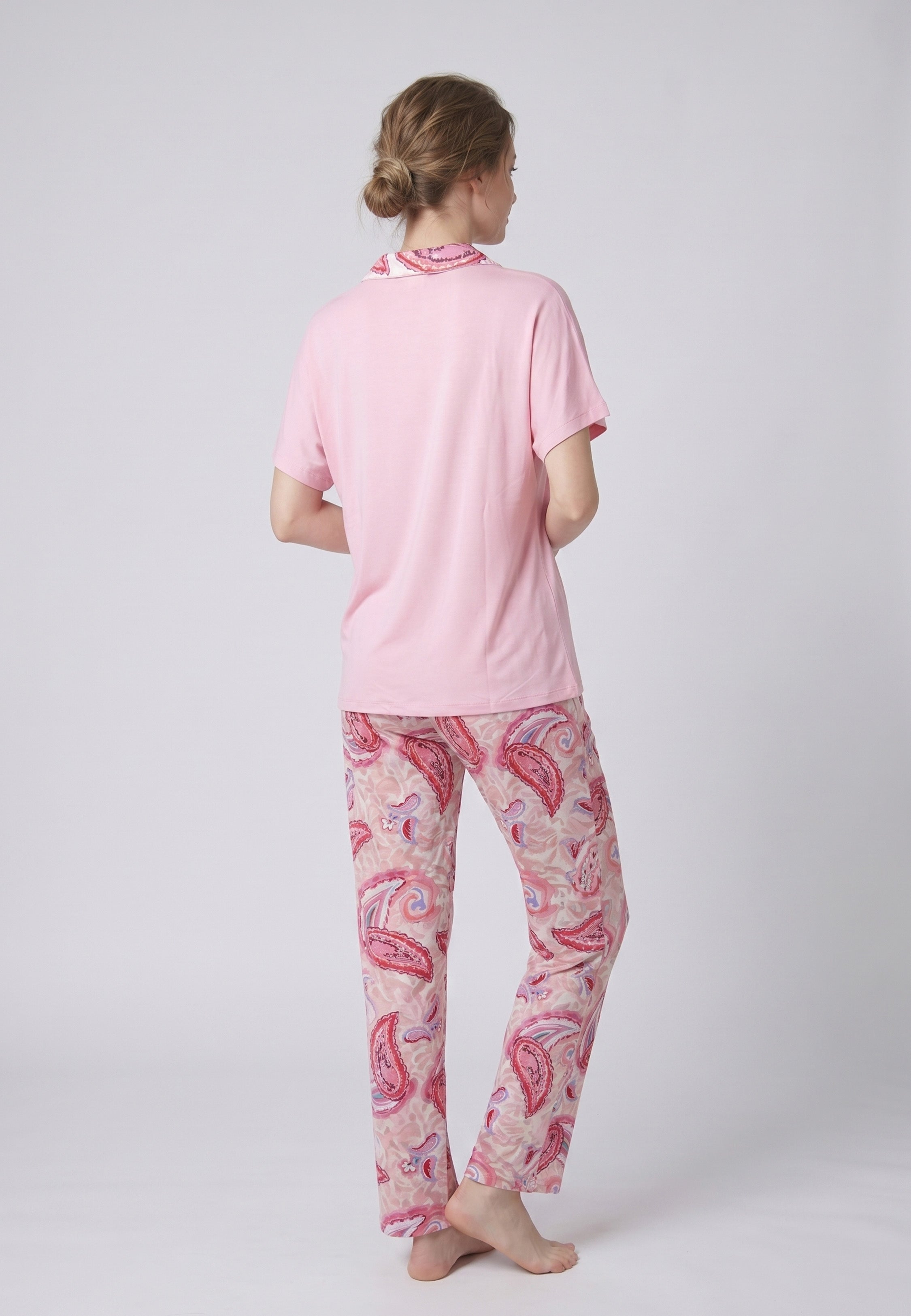 Femme portant un pyjama deux pièces chemise boutonnée manches courtes unie rose liseré imprimé paisley et pantalon droit imprimé paisley multicolore rose et rouge Rosabella Ethnique 2