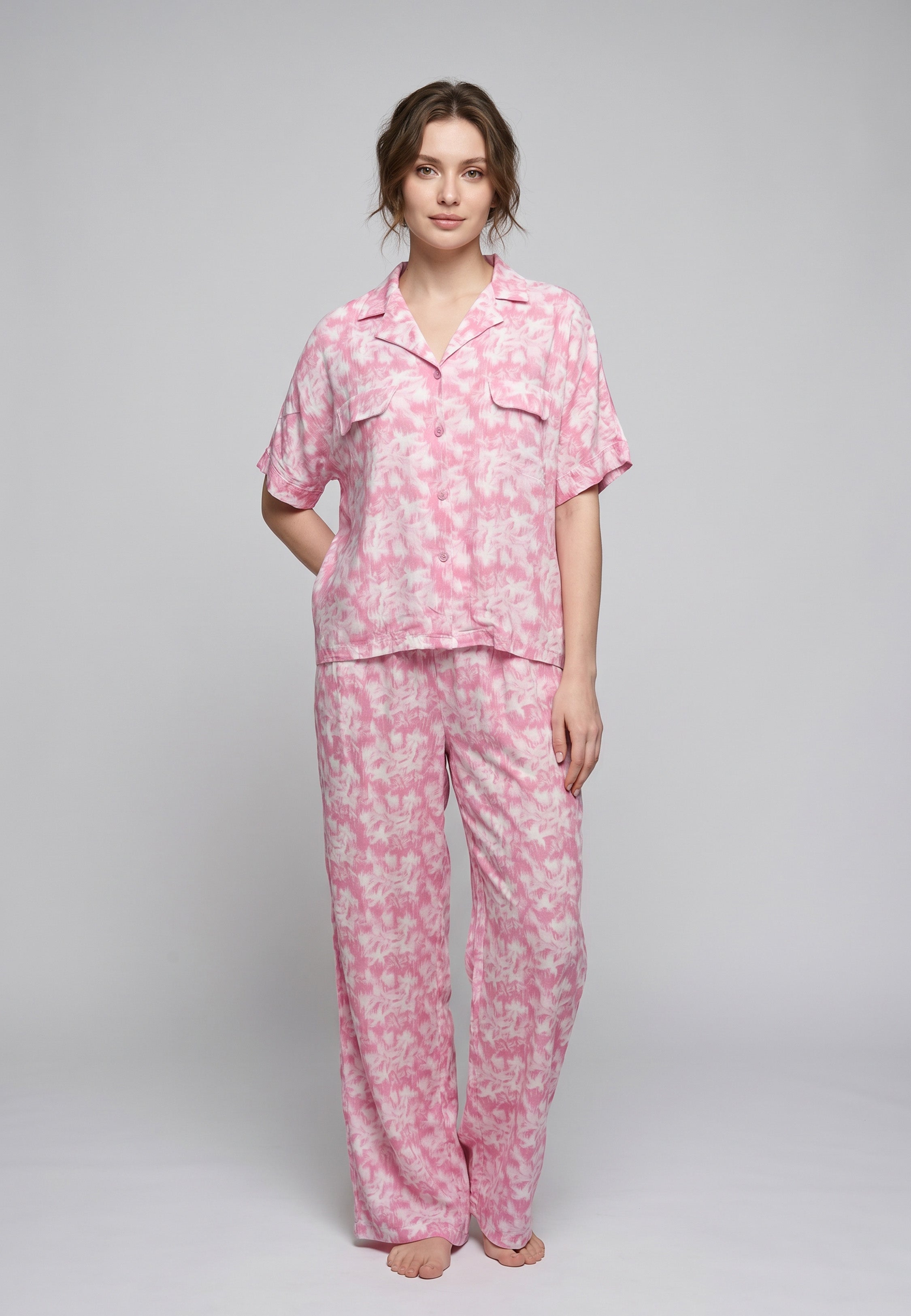Femme portant un pyjama deux pièces chemise boutonnée manches courtes et pantalon large imprimé aquarelle rose clair et blanc Rosabella Aurora Line