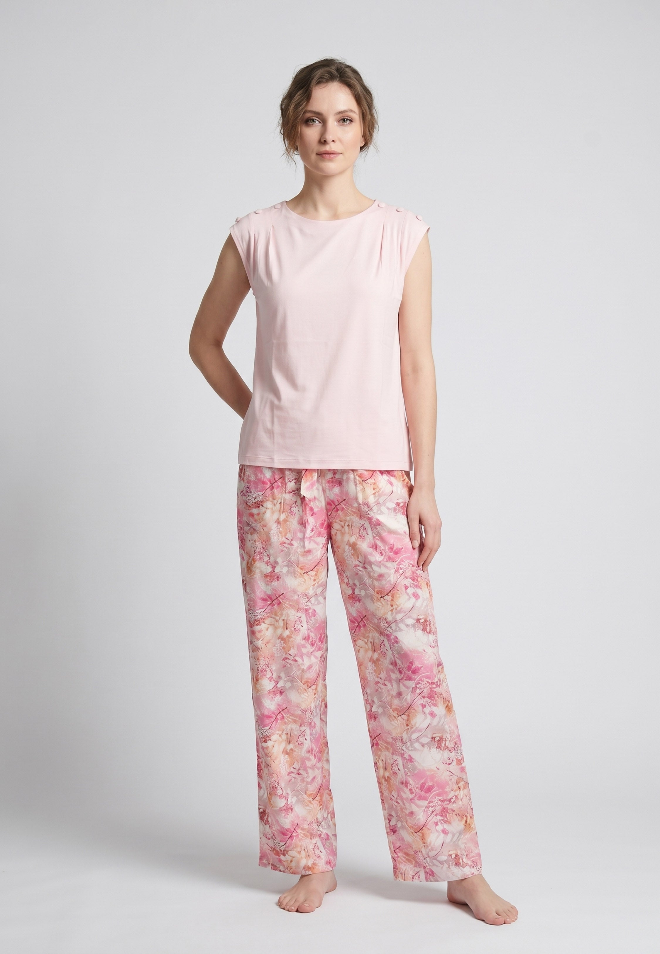 Femme portant un pyjama deux pièces top sans manches boutons épaule uni rose clair et pantalon large imprimé floral aquarelle rose et orangé Rosabella Soft Reflections