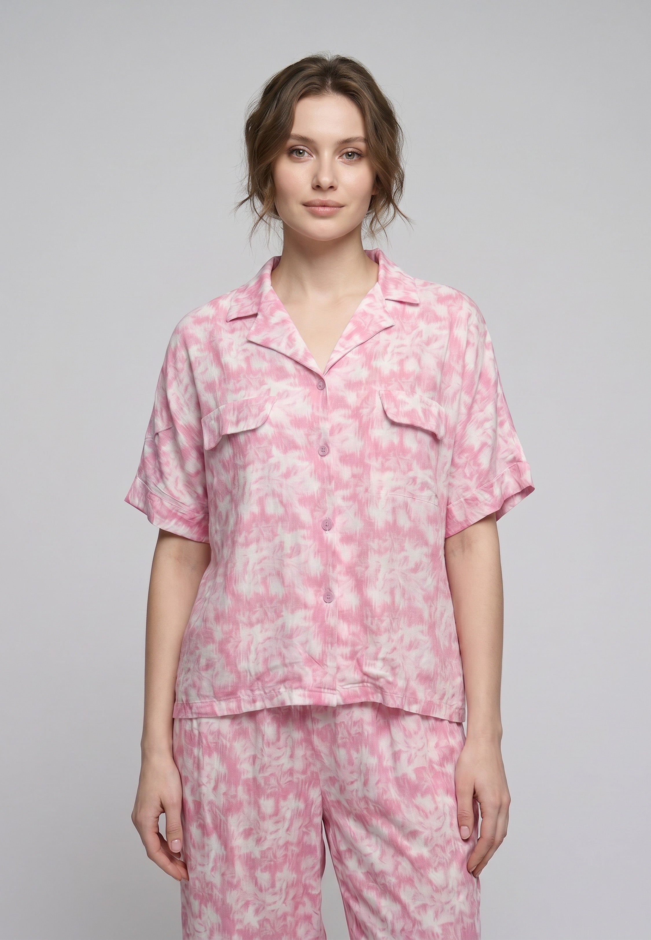 Femme portant un pyjama deux pièces chemise boutonnée manches courtes et pantalon large imprimé aquarelle rose clair et blanc Rosabella Aurora Line