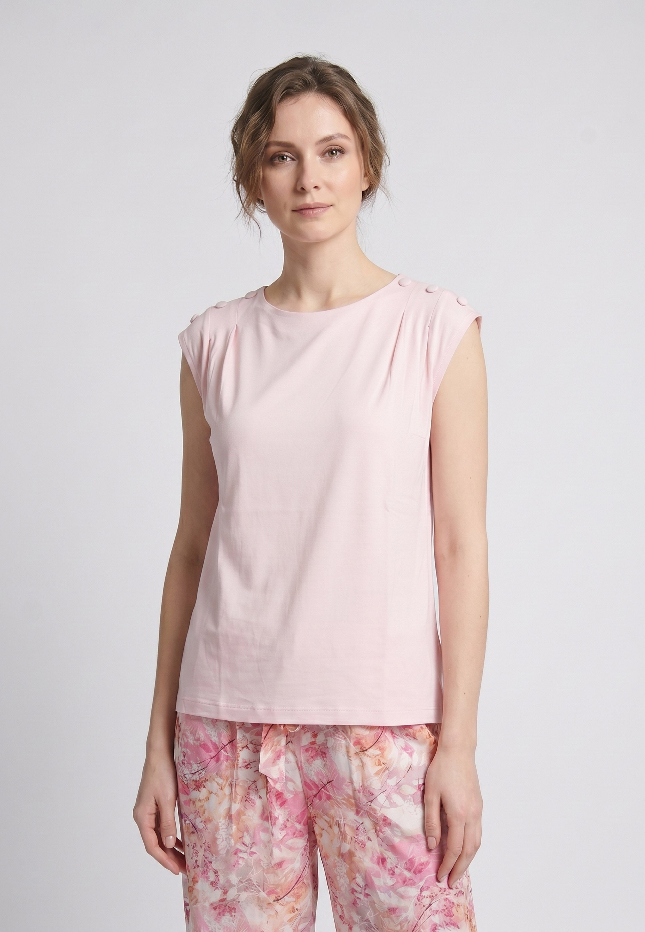Femme portant un pyjama deux pièces top sans manches boutons épaule uni rose clair et pantalon large imprimé floral aquarelle rose et orangé Rosabella Soft Reflections