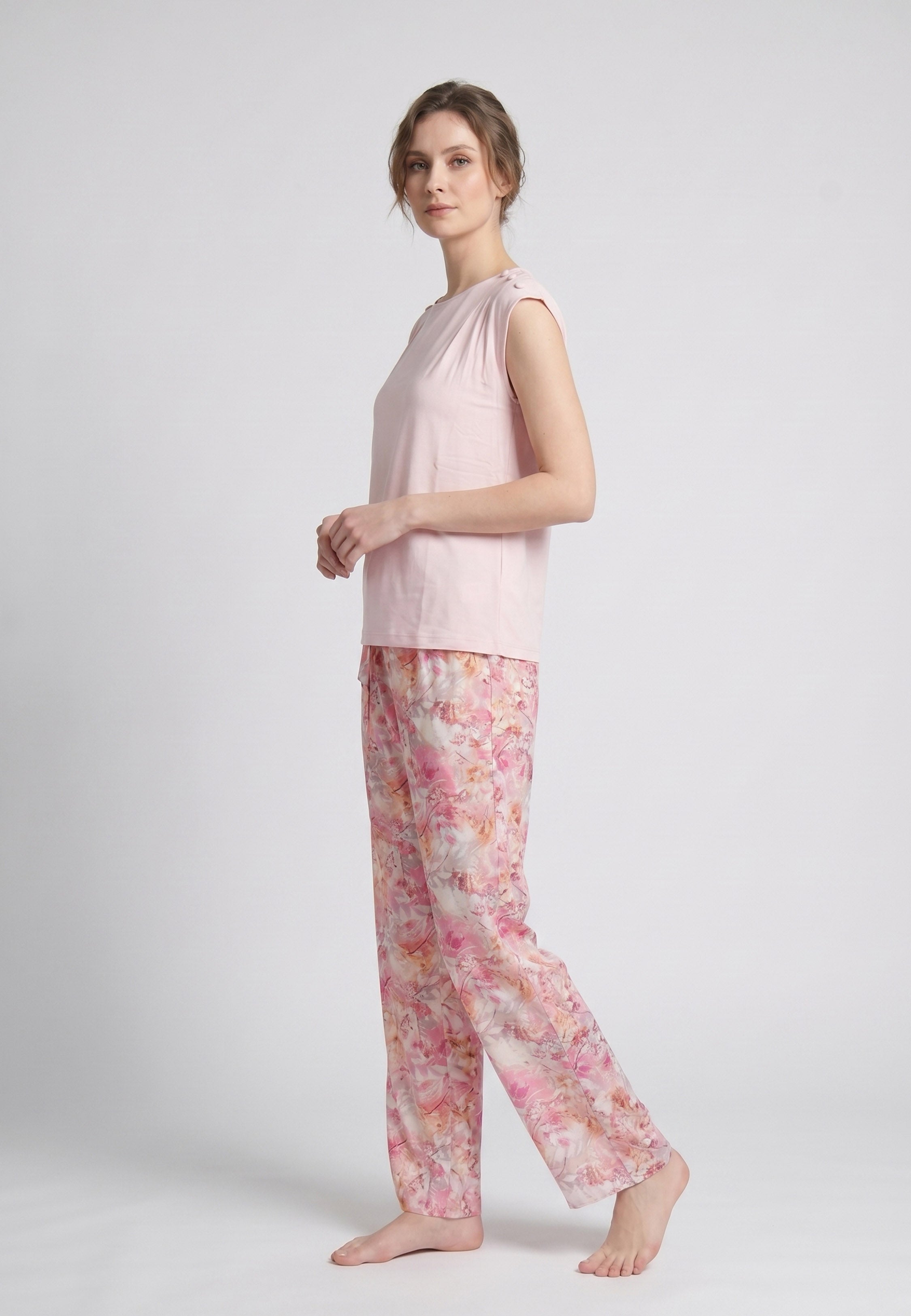 Femme portant un pyjama deux pièces top sans manches boutons épaule uni rose clair et pantalon large imprimé floral aquarelle rose et orangé Rosabella Soft Reflections