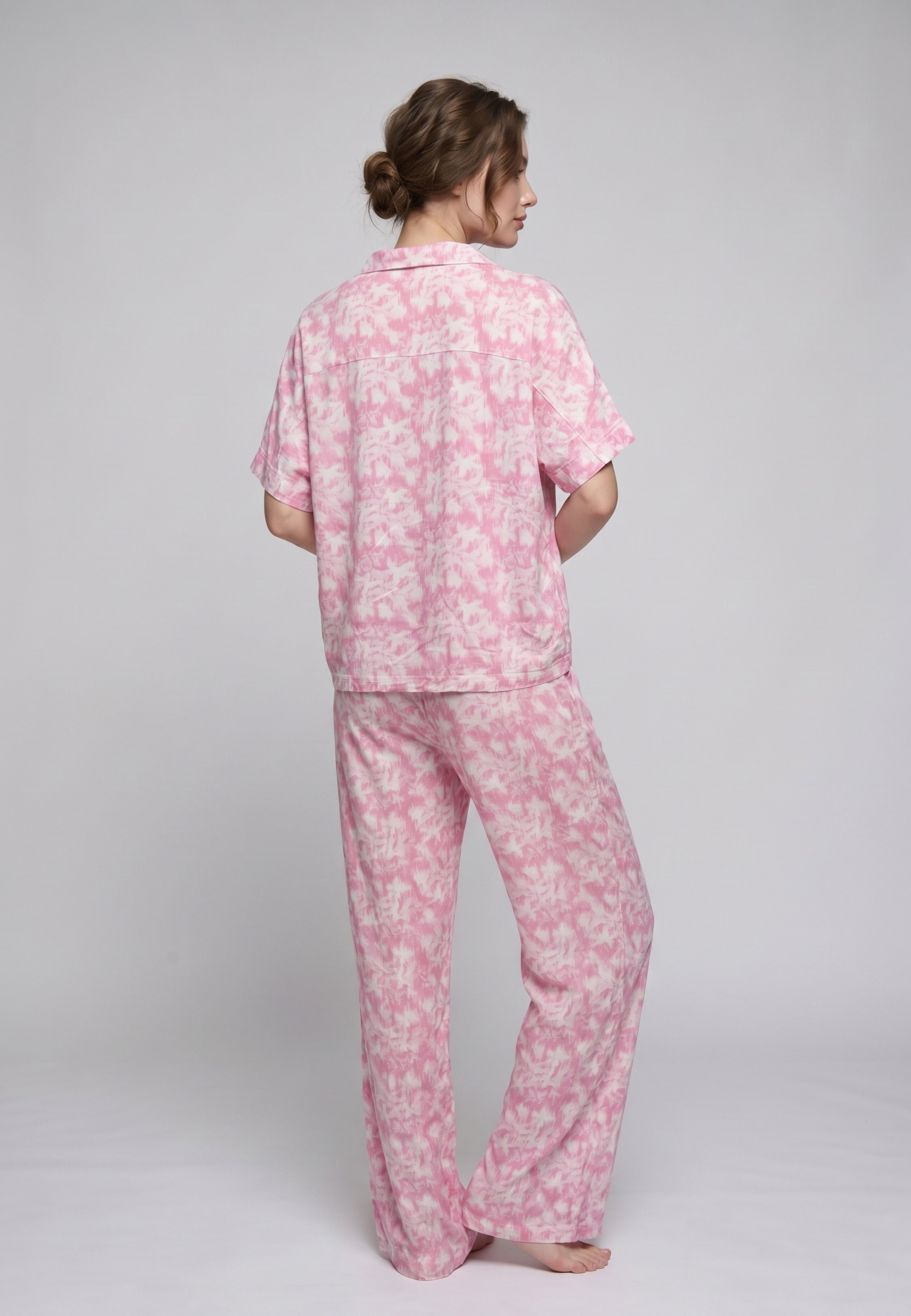 Femme portant un pyjama deux pièces chemise boutonnée manches courtes et pantalon large imprimé aquarelle rose clair et blanc Rosabella Aurora Line