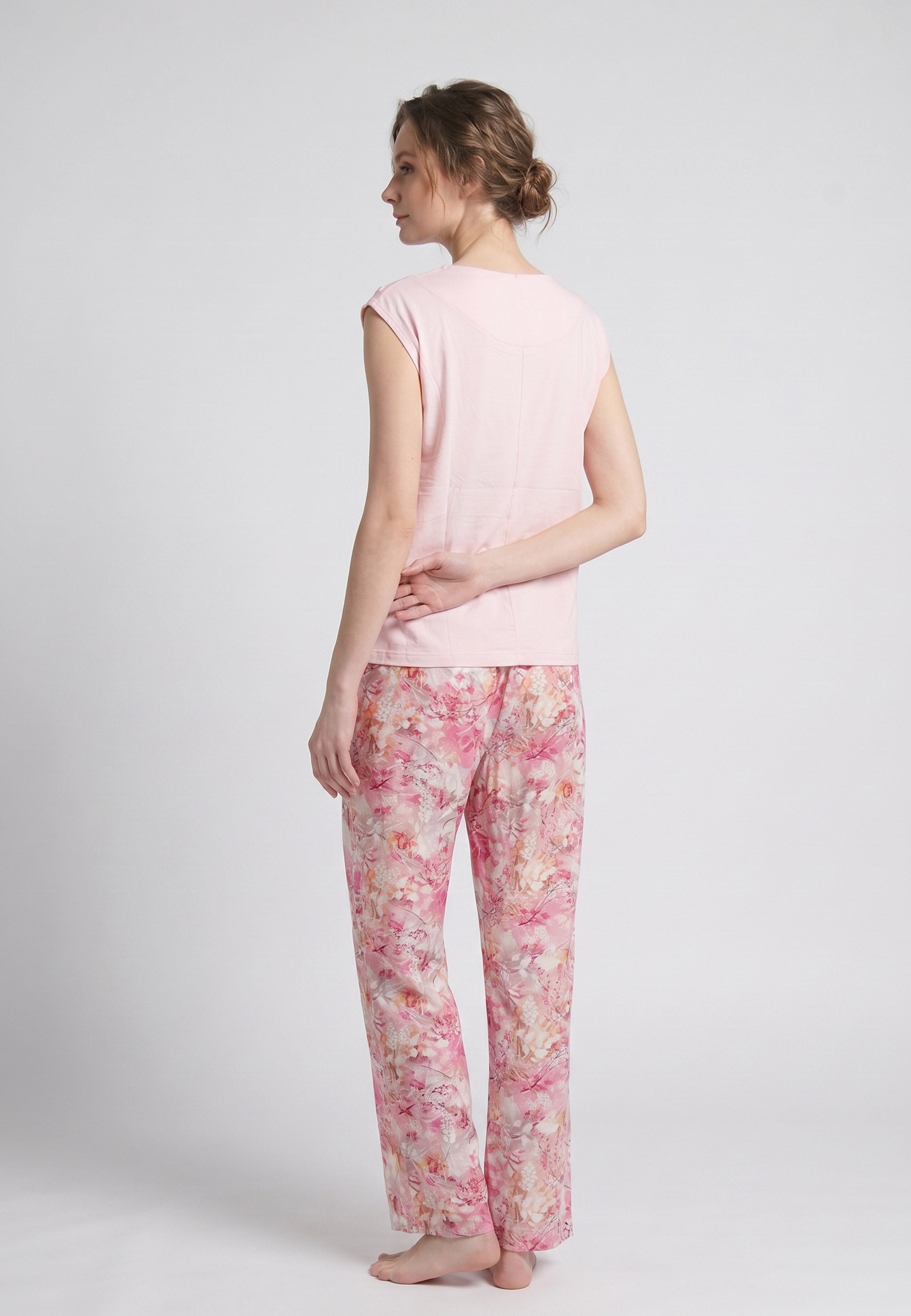 Femme portant un pyjama deux pièces top sans manches boutons épaule uni rose clair et pantalon large imprimé floral aquarelle rose et orangé Rosabella Soft Reflections