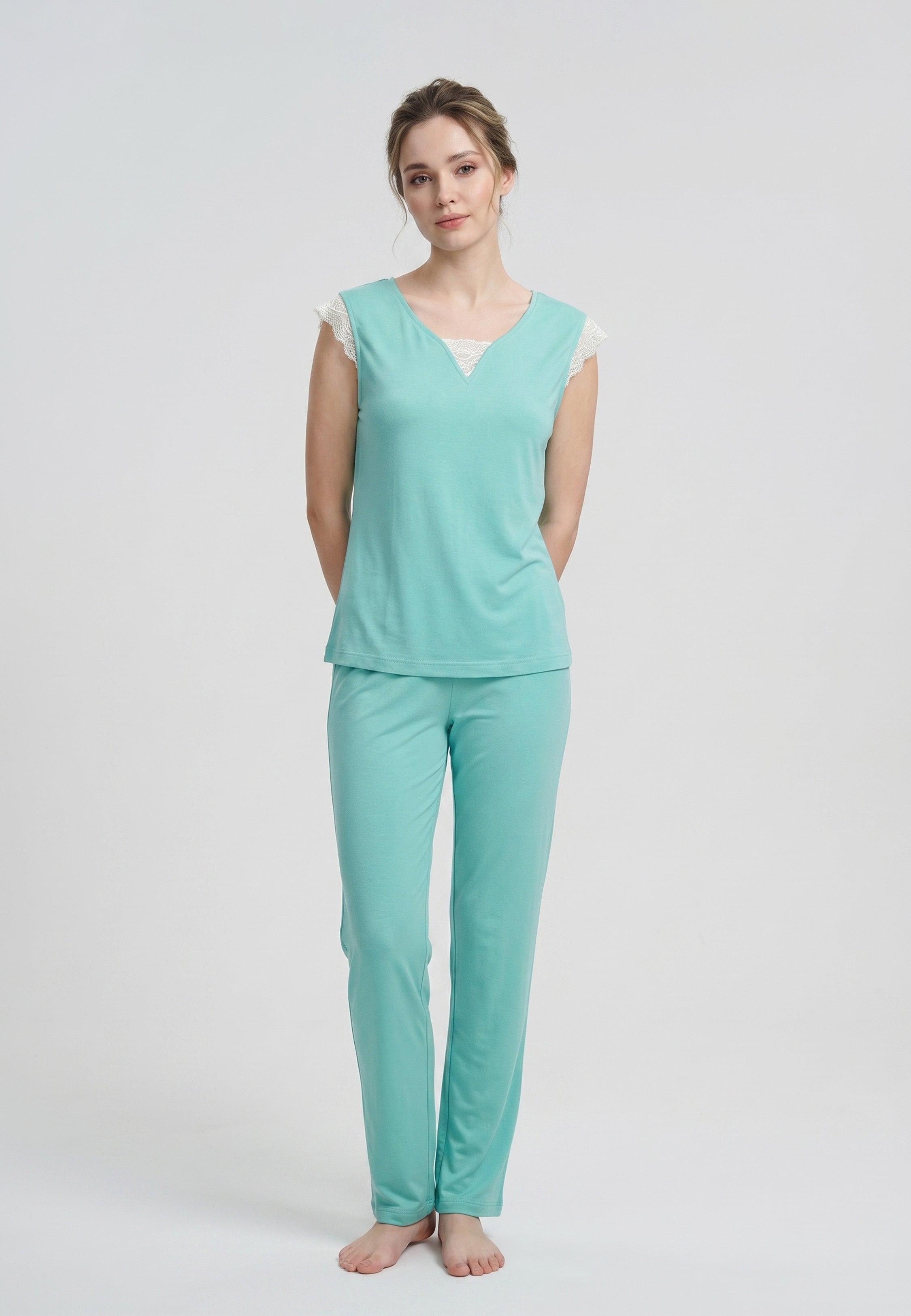Femme portant un pyjama deux pièces uni vert avec détails en dentelle crème et pantalon assorti
