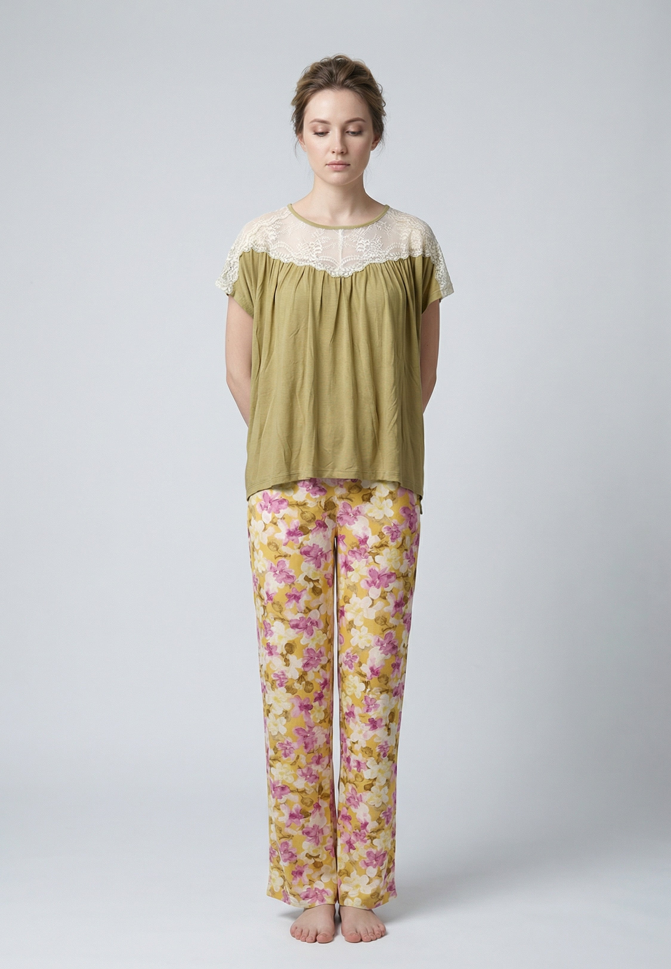 Femme portant un pyjama deux pièces haut moutarde avec empiècement dentelle crème et pantalon à imprimé floral rose et jaune