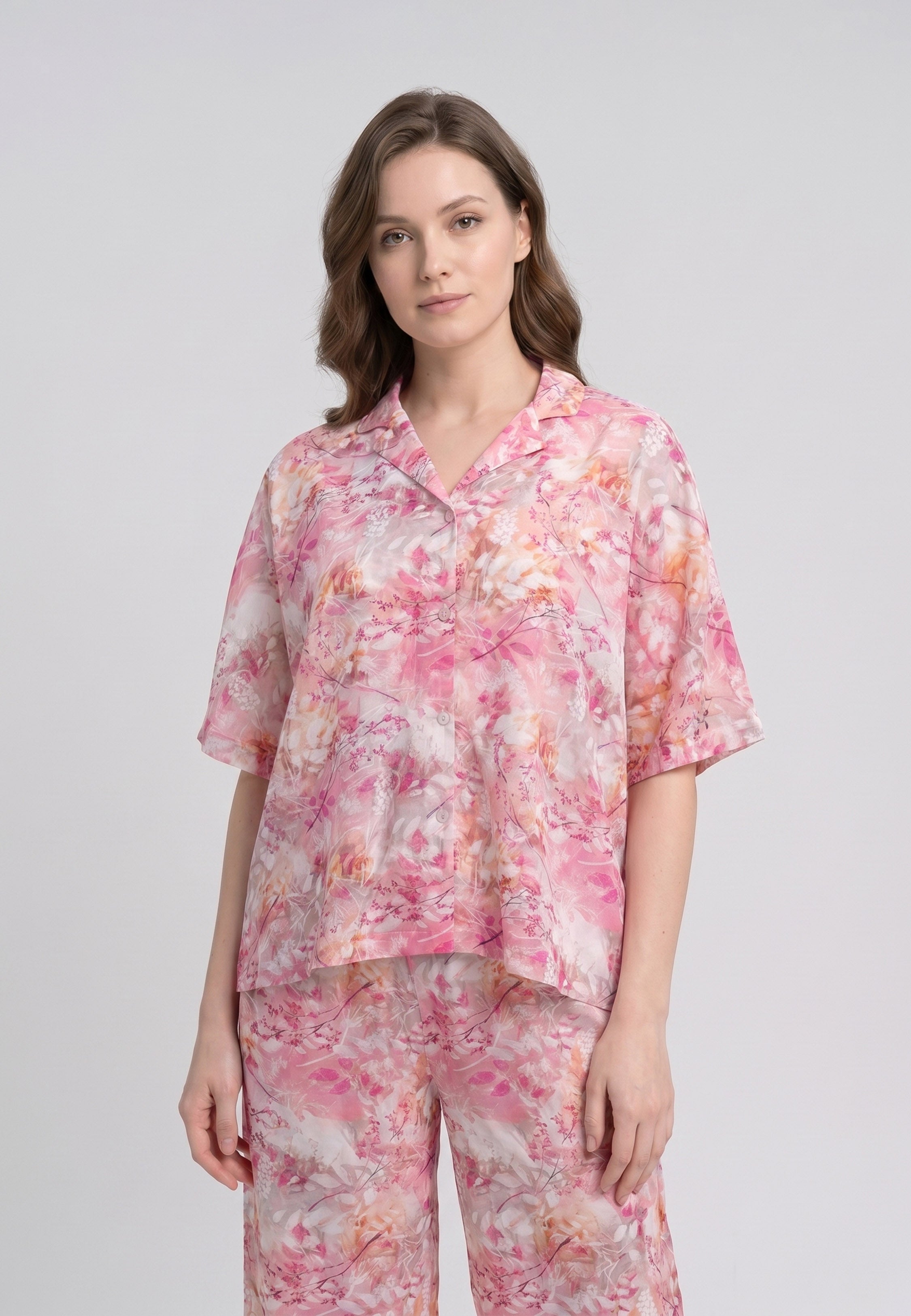 Femme portant un pyjama deux pièces chemise boutonnée col revers imprimé floral aquarelle rose et orangé et pantalon large assorti Rosabella Soft Reflections
