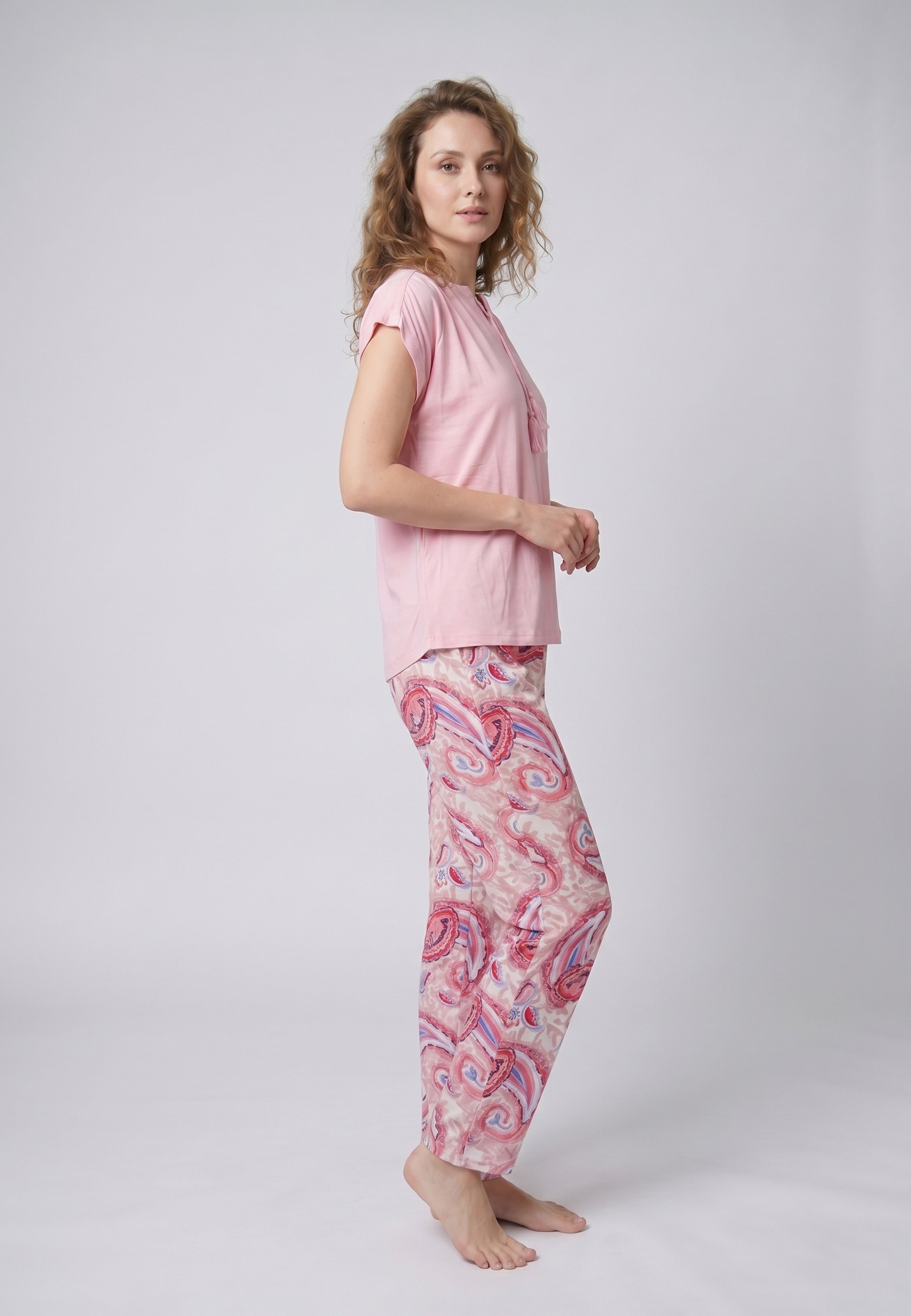 Femme portant un pyjama deux pièces top col V à lien frontal pompons uni rose et pantalon droit imprimé paisley multicolore rose et rouge Rosabella Ethnique 2