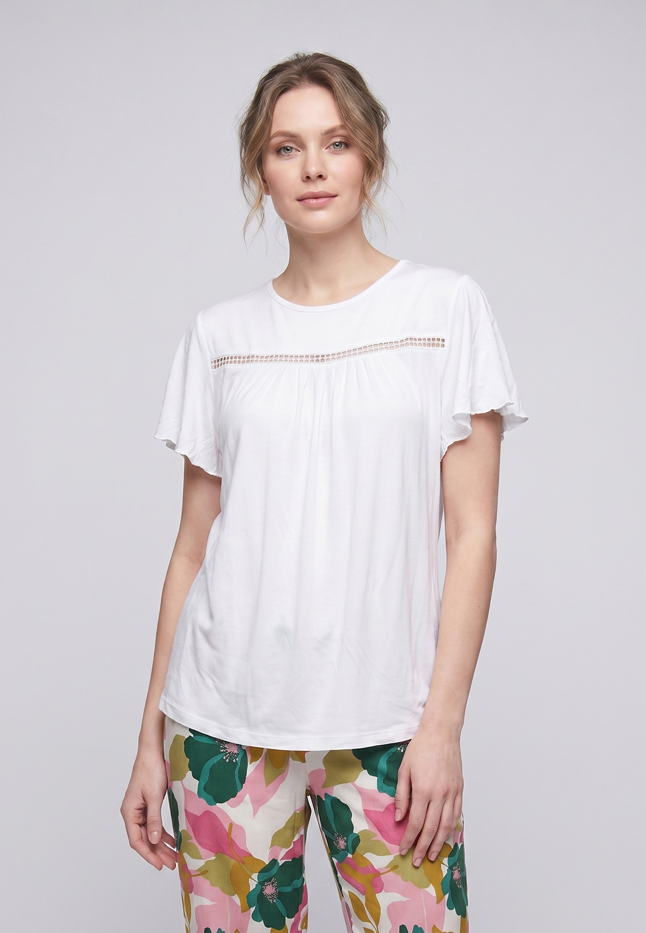 Femme portant un pyjama deux pièces t-shirt blanc manches volantées broderie anglaise et pantalon large grand imprimé floral coloré Rosabella Juliet Rose