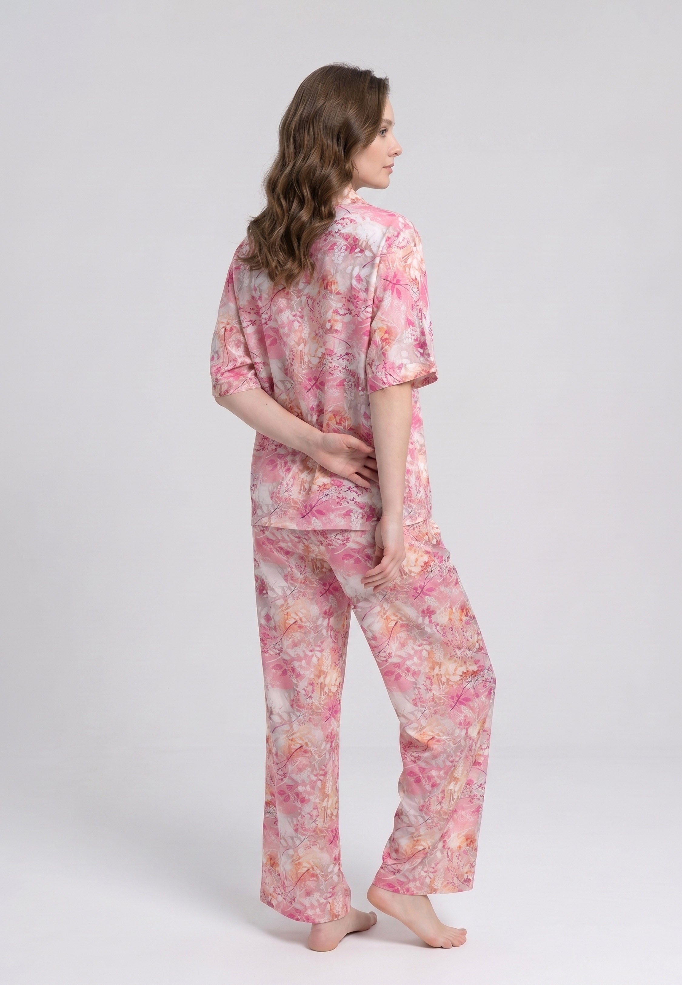 Femme portant un pyjama deux pièces chemise boutonnée col revers imprimé floral aquarelle rose et orangé et pantalon large assorti Rosabella Soft Reflections