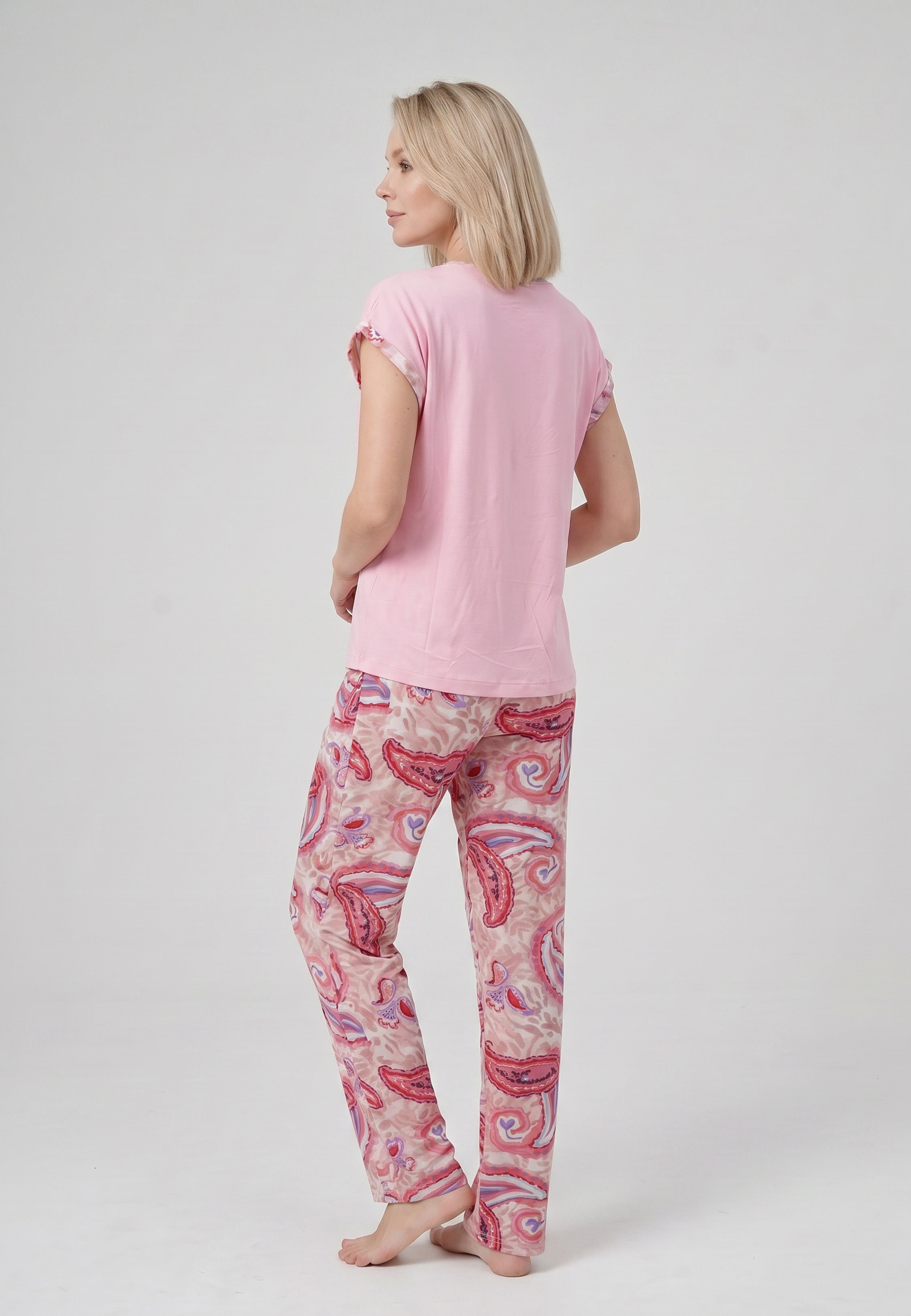 Femme portant un pyjama deux pièces t-shirt col rond uni rose liseré imprimé paisley et pantalon droit imprimé paisley multicolore rose et rouge Rosabella Ethnique 2