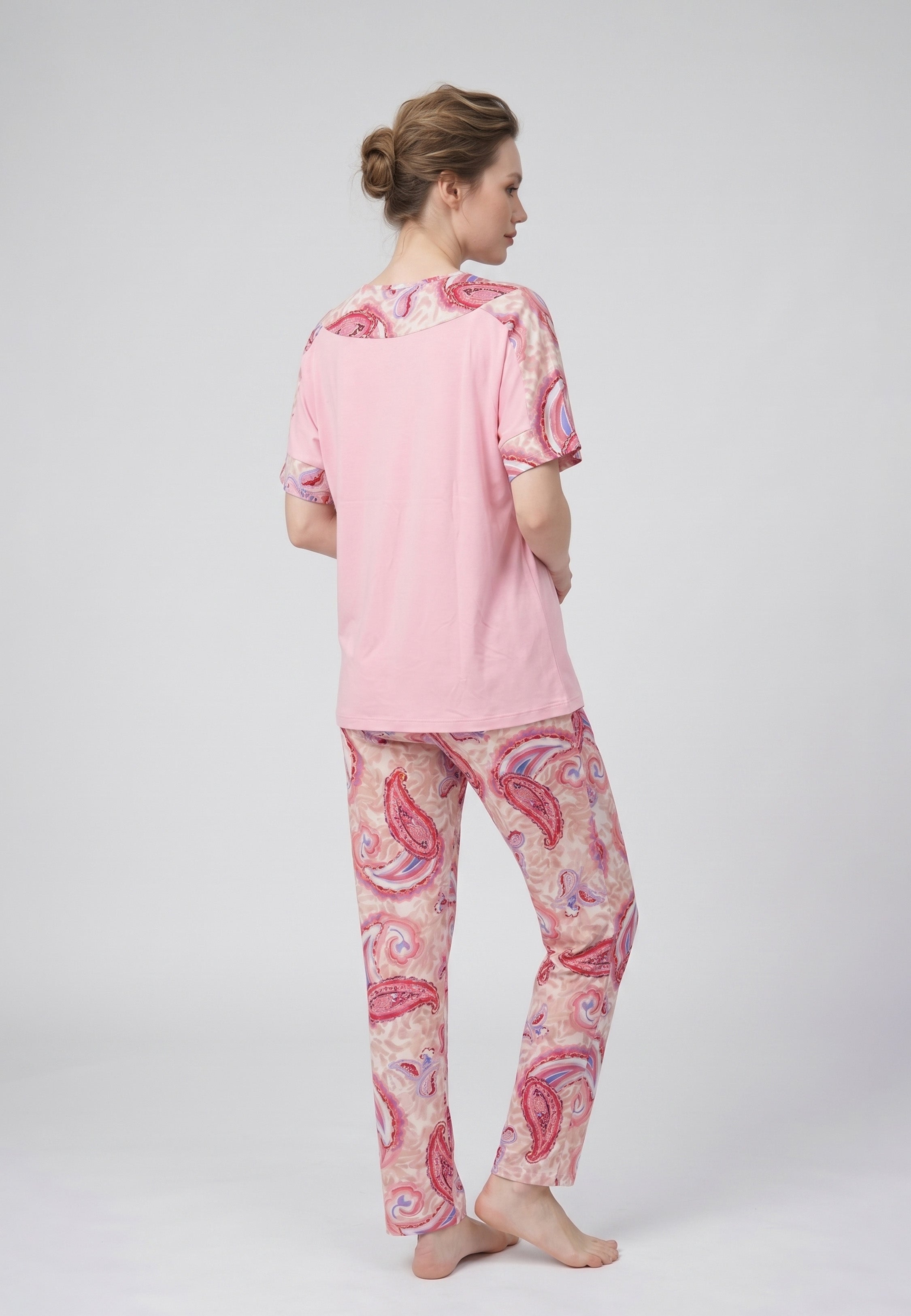 Femme portant un pyjama deux pièces t-shirt col rond uni rose empiècement imprimé paisley et pantalon droit imprimé paisley multicolore rose et rouge Rosabella Ethnique 2