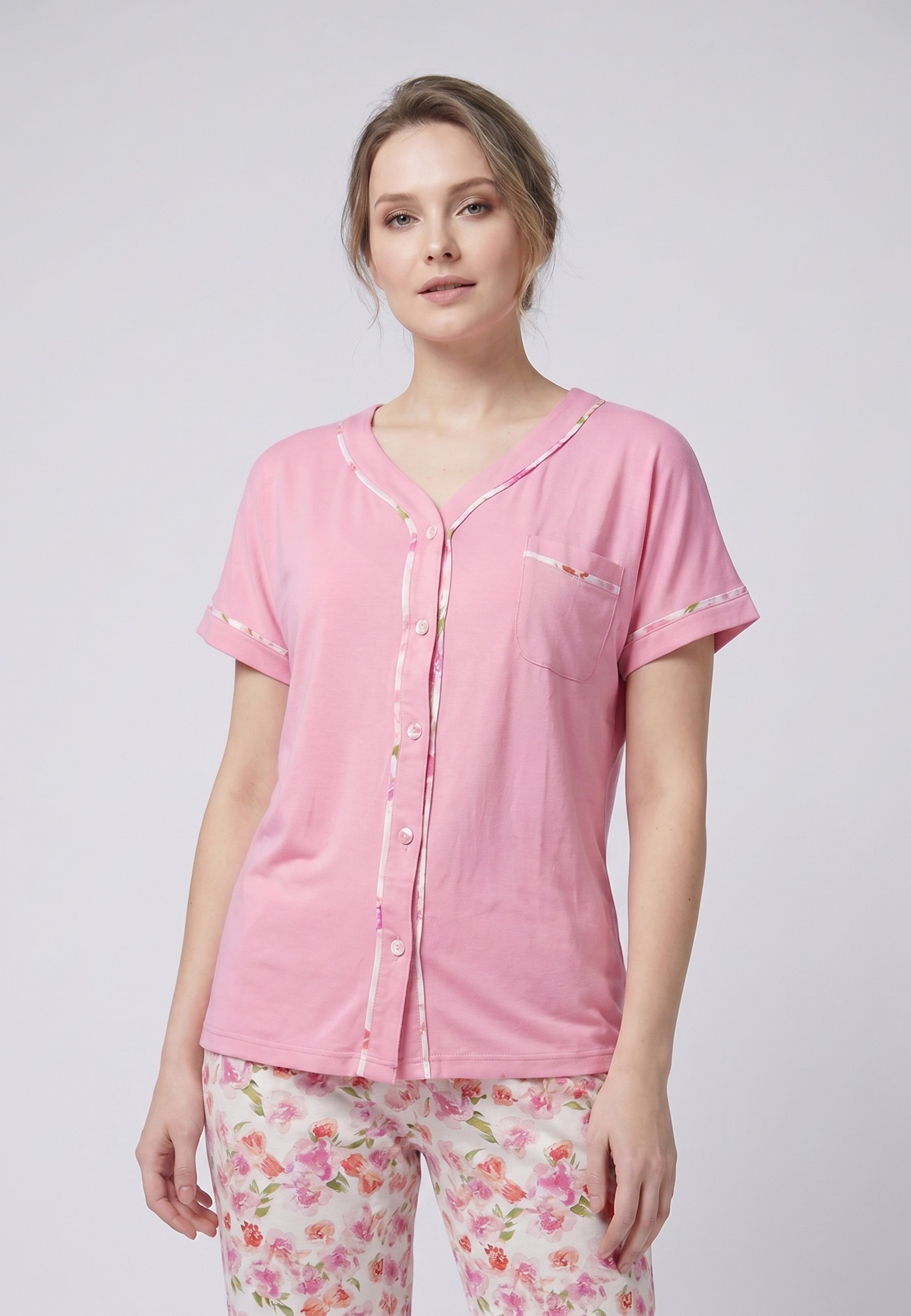 Femme portant un pyjama deux pièces chemise boutonnée manches courtes rose unie liseré fleuri et pantalon long imprimé fleuri multicolore Rosabella Floralys
