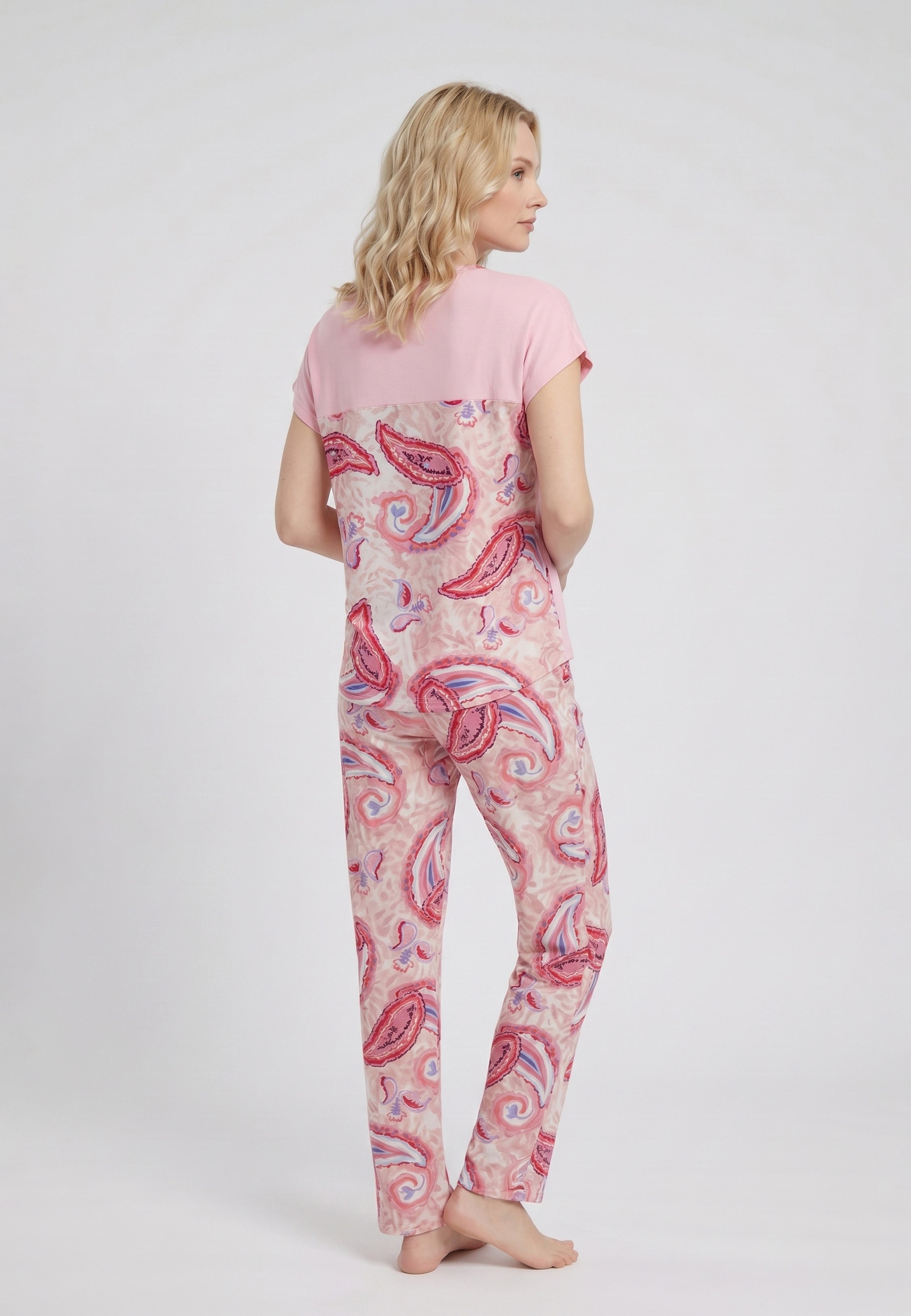 Femme portant un pyjama deux pièces t-shirt oversize col rond uni rose poche poitrine imprimée paisley et pantalon droit imprimé paisley multicolore rose et rouge Rosabella Ethnique 2