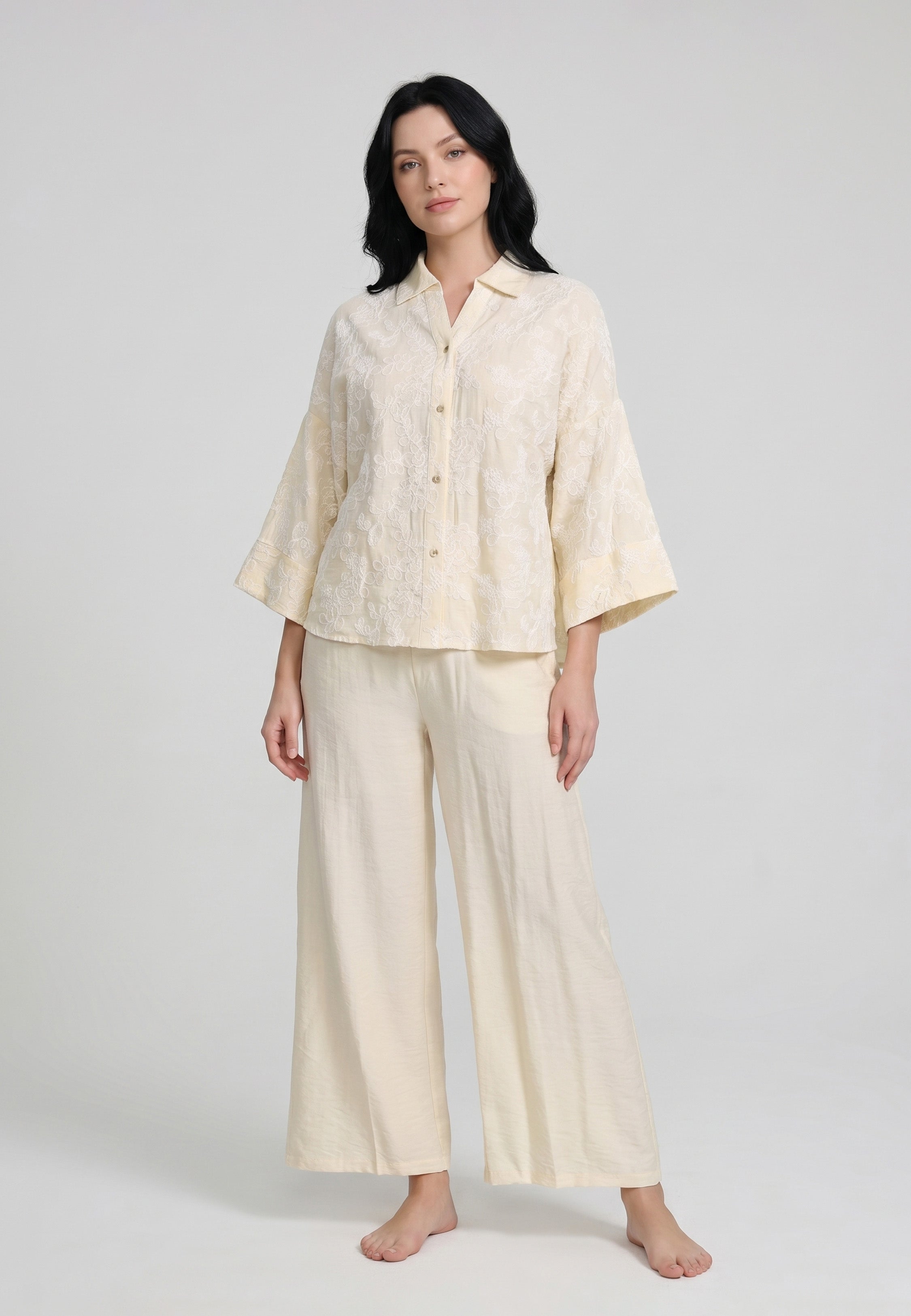 Femme portant un ensemble chemise col camp boutonnée manches évasées broderie perforée florale jaune pâle et pantalon large uni jaune pâle Rosabella