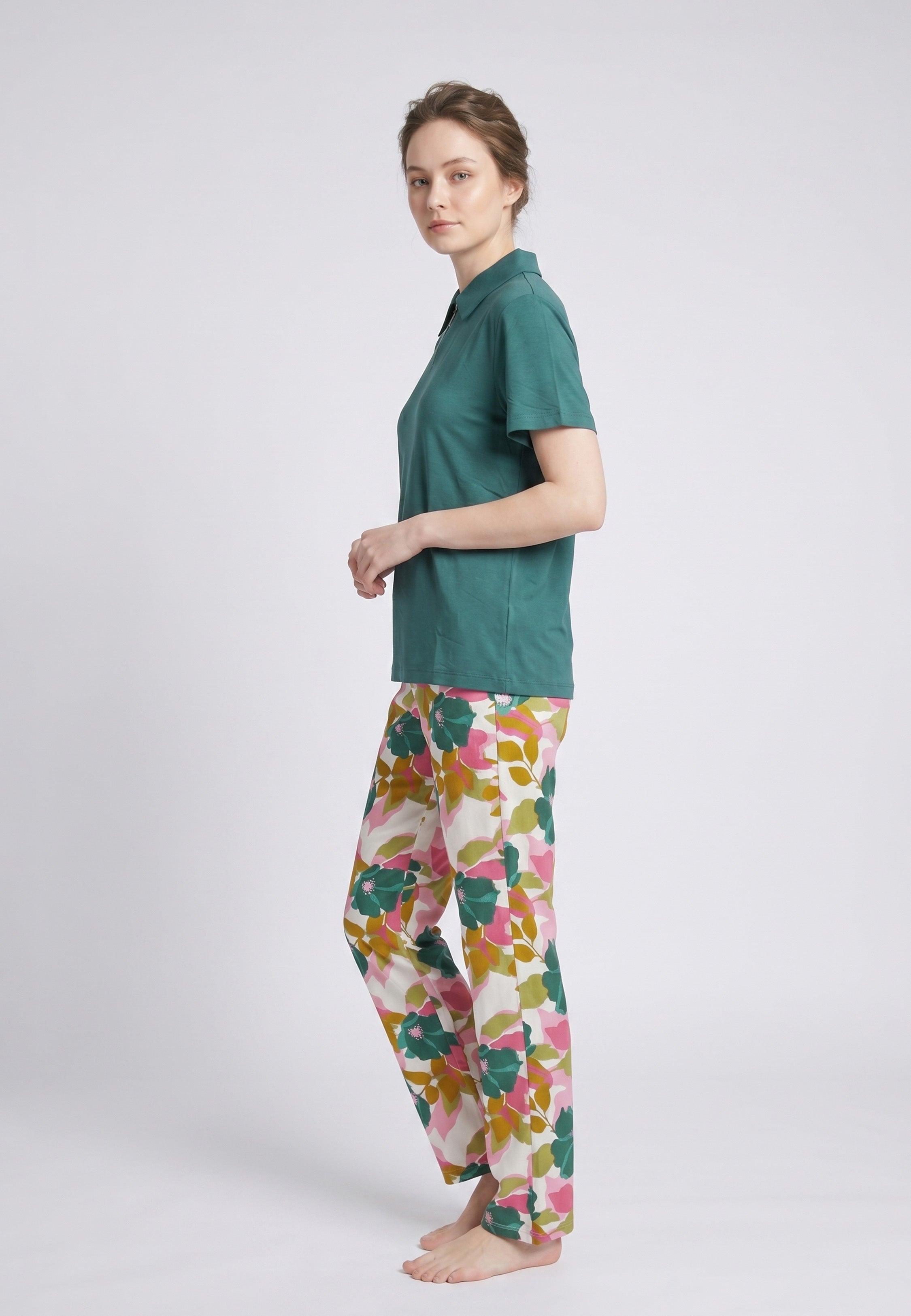 Femme portant un pyjama deux pièces top col polo zippé uni vert sapin et pantalon large grand imprimé fleuri multicolore vert rose et kaki Rosabella Mellow Moments
