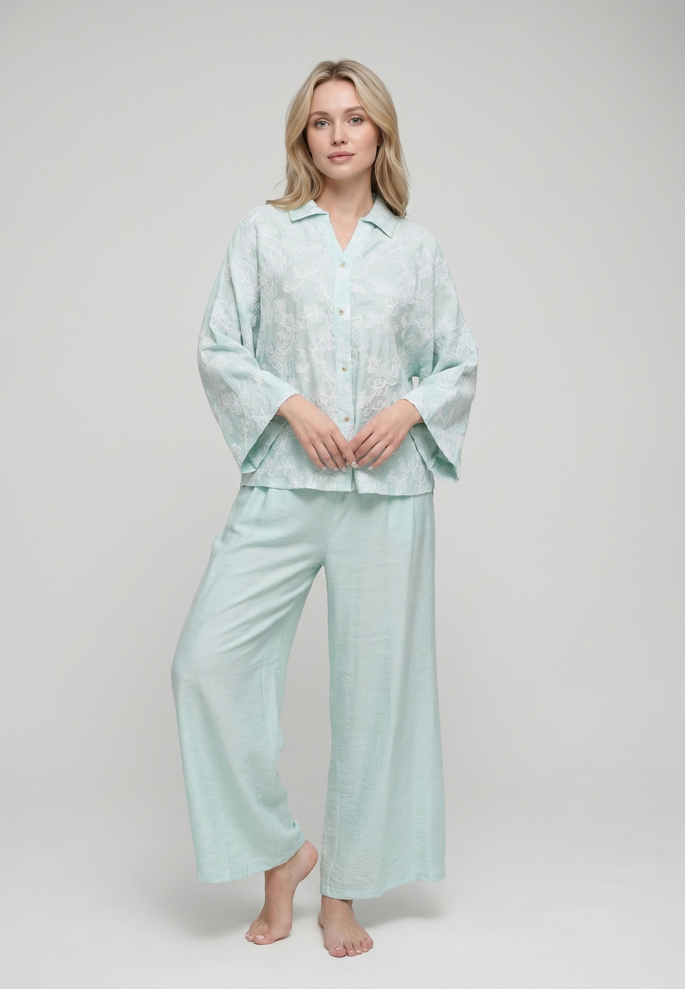 Femme portant un ensemble chemise col camp boutonnée manches évasées broderie perforée florale vert d'eau et pantalon large uni vert d'eau Rosabella