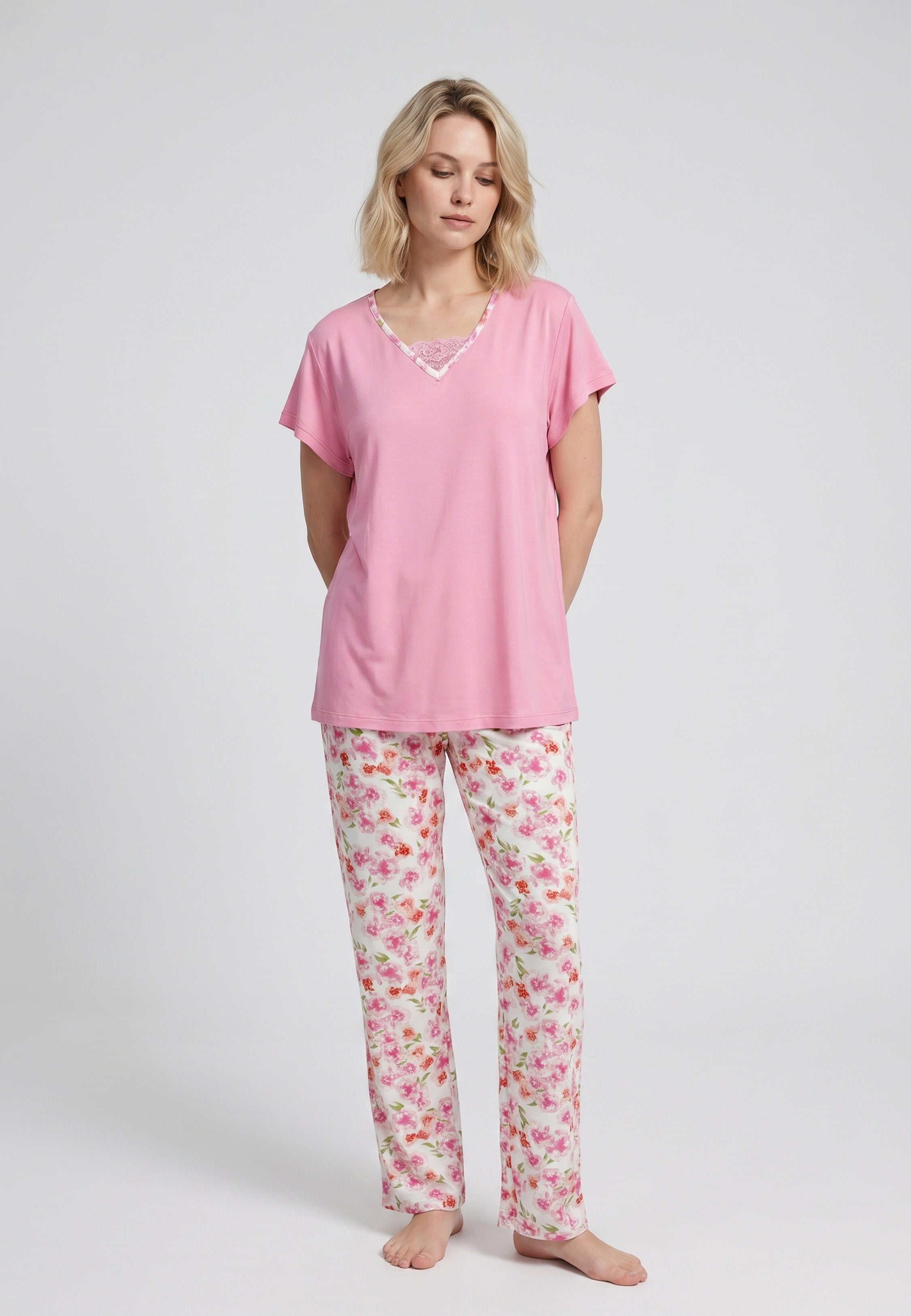 Femme portant un pyjama deux pièces t-shirt rose col V liseré dentelle et pantalon long imprimé fleuri multicolore Rosabella Floralys