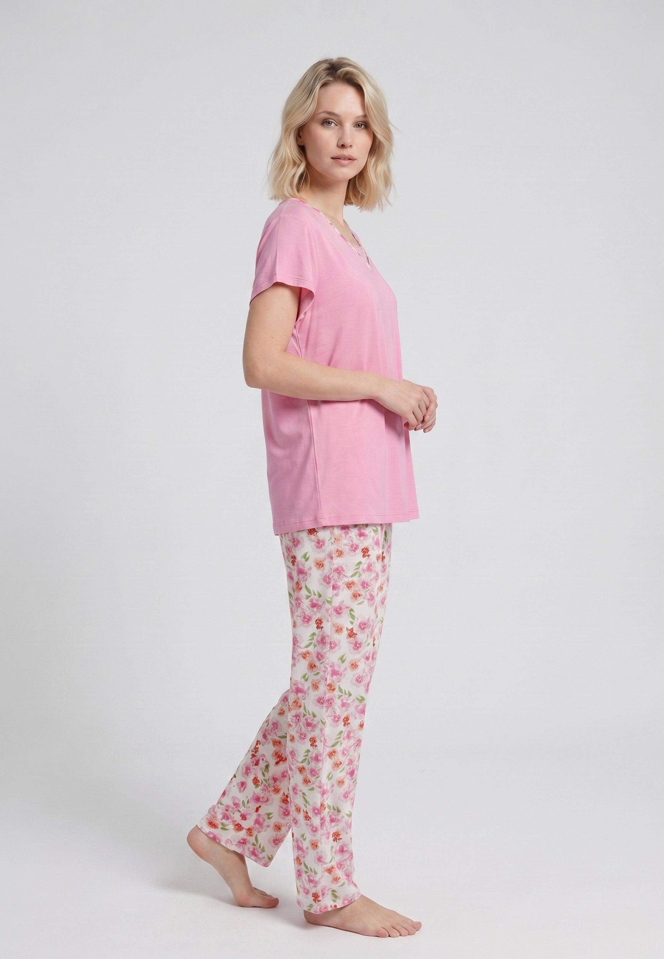 Femme portant un pyjama deux pièces t-shirt rose col V liseré dentelle et pantalon long imprimé fleuri multicolore Rosabella Floralys