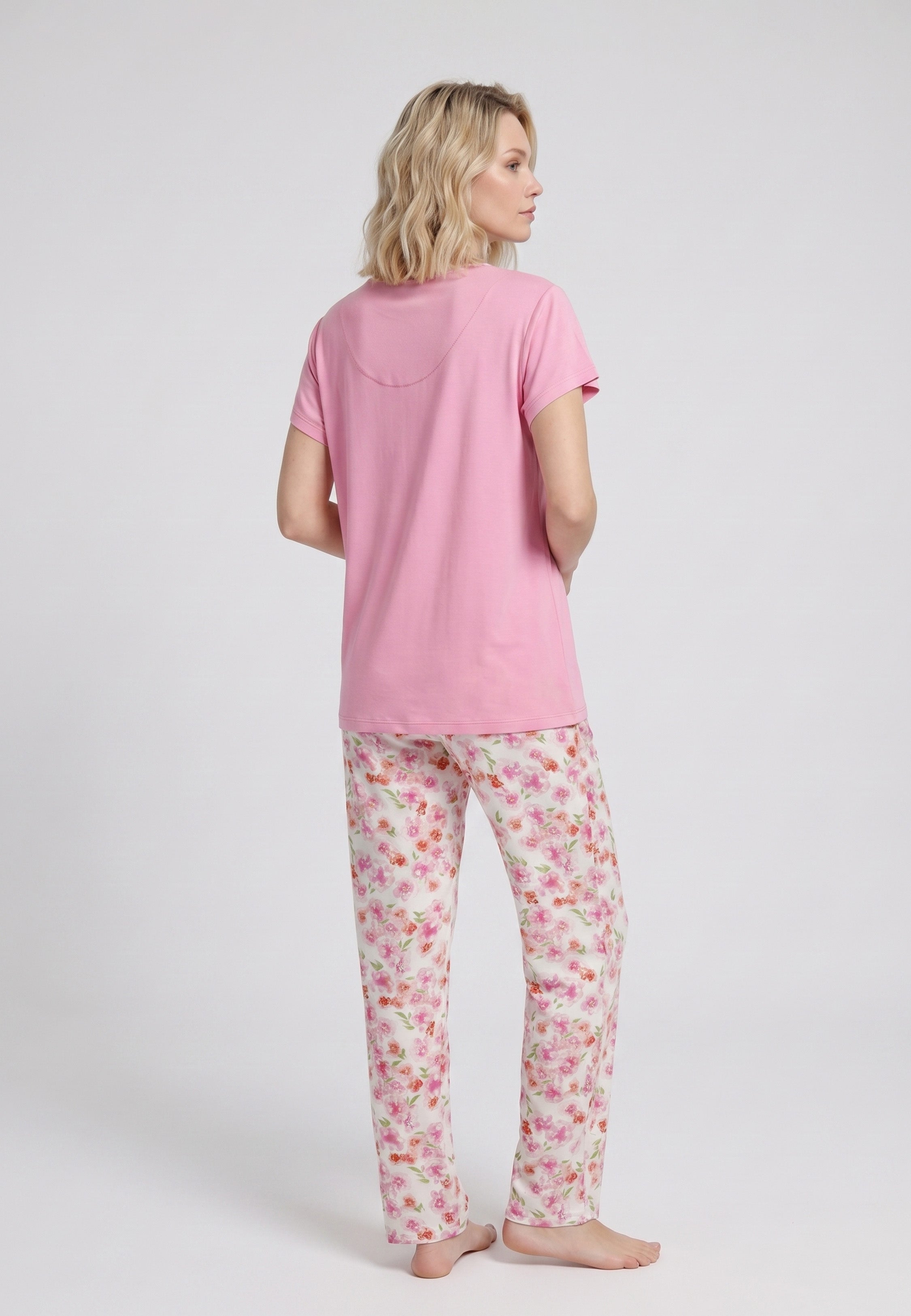 Femme portant un pyjama deux pièces t-shirt rose col V liseré dentelle et pantalon long imprimé fleuri multicolore Rosabella Floralys