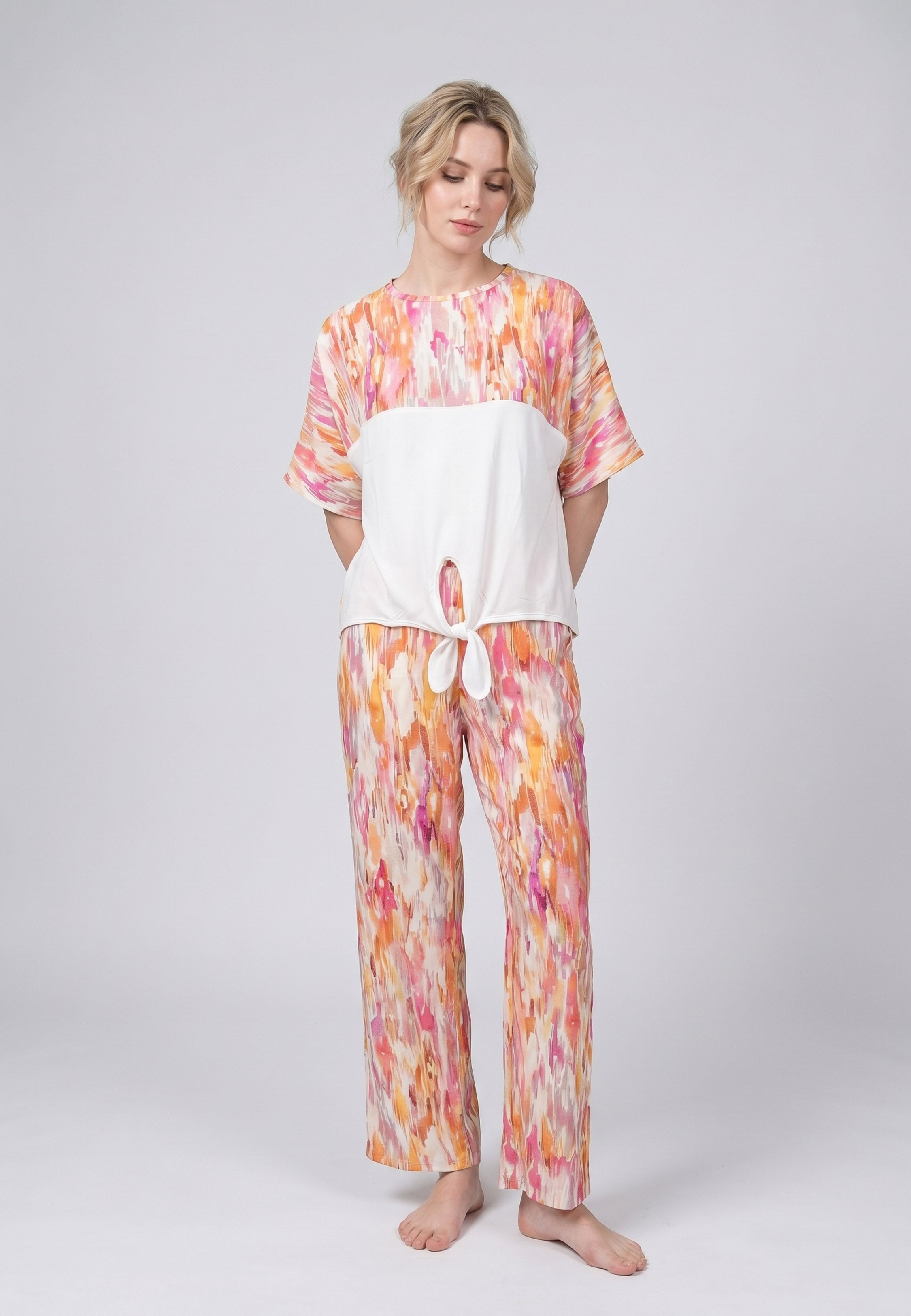 Femme portant un pyjama deux pièces top col rond bicolore nœud frontal imprimé aquarelle et pantalon large imprimé aquarelle abstrait jaune Rosabella Soft Embrace