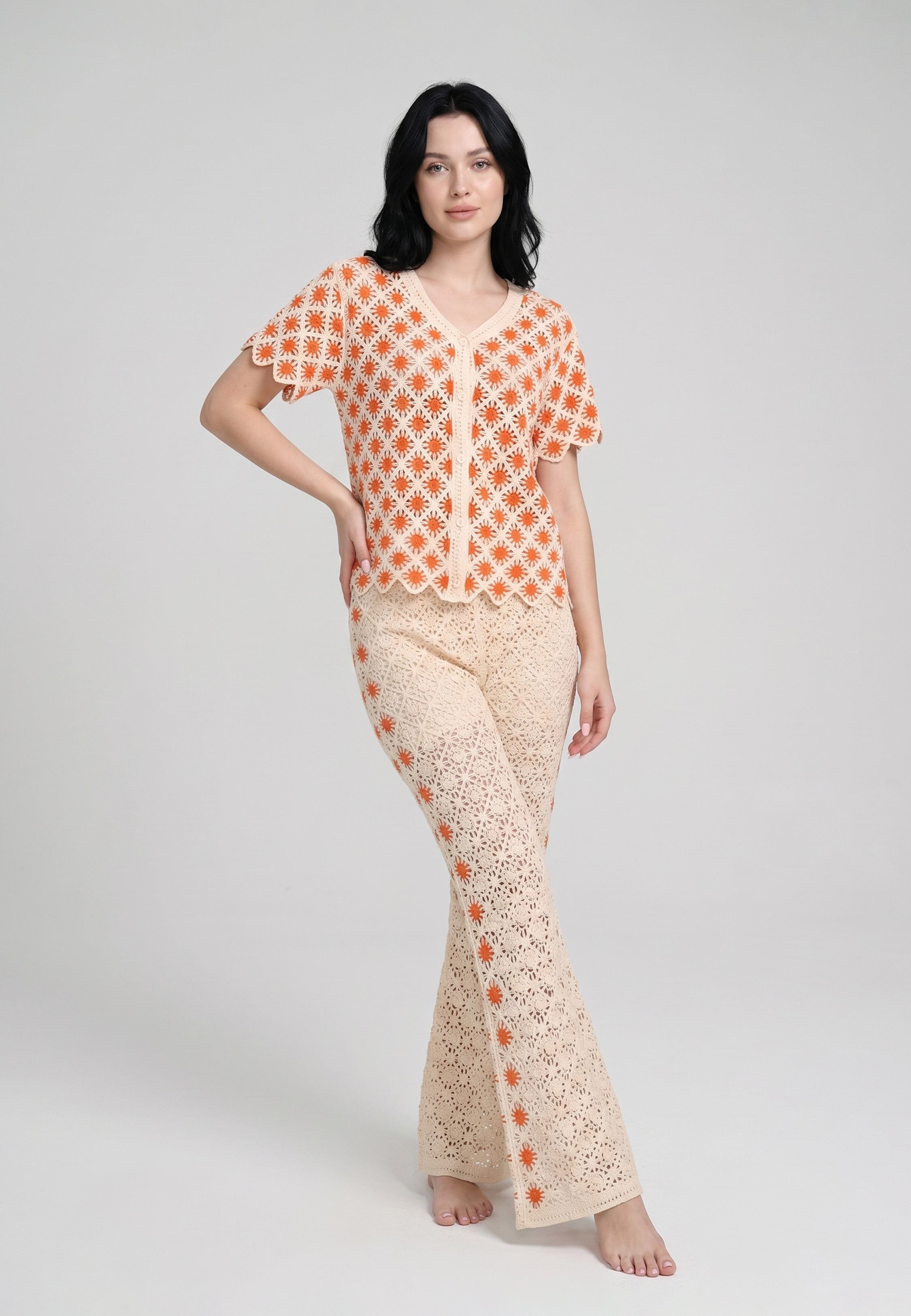 Femme portant un ensemble top boutonné crochet motifs fleurs soleil bicolore crème orange et pantalon bootcut assorti Rosabella